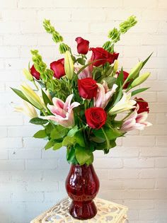 Red roses and pink lilies in a red glass vase