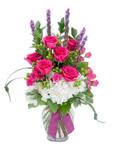 Pink roses and white hydrangeas in a glass vase with a ribbon