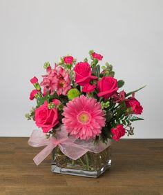 Pink mixed flower arrangement in a square glass vase with a ribbon