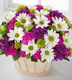 Bouquet of white daisies and purple-pink flowers in a round basket