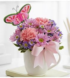 Pink and purple bouquet in a white mug with a butterfly pick
