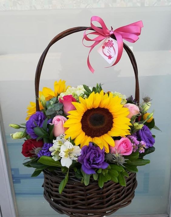 Basket of mixed flowers with a large sunflower and pink ribbon