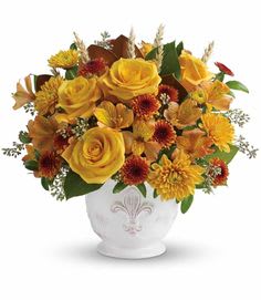 Yellow roses and orange mums arranged in a white vase