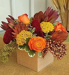 Orange and burgundy floral arrangement in a square box