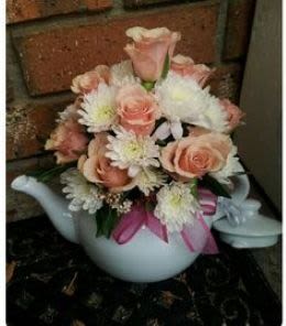 Pink and white flower arrangement in a white teapot