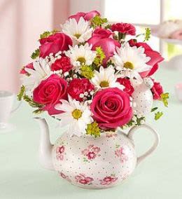 Pink roses and white daisies arranged in a floral teapot