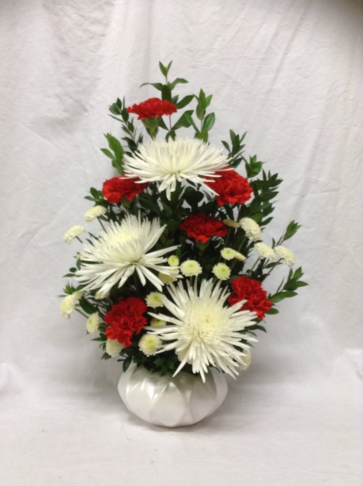 White spider mums and red carnations in a white vase