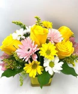 Yellow roses and pink, white, and yellow daisies in a vase