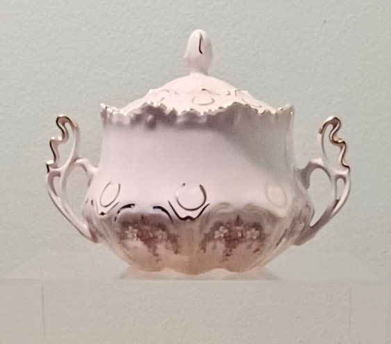 A pale pink decorative lidded bowl with ornate handles