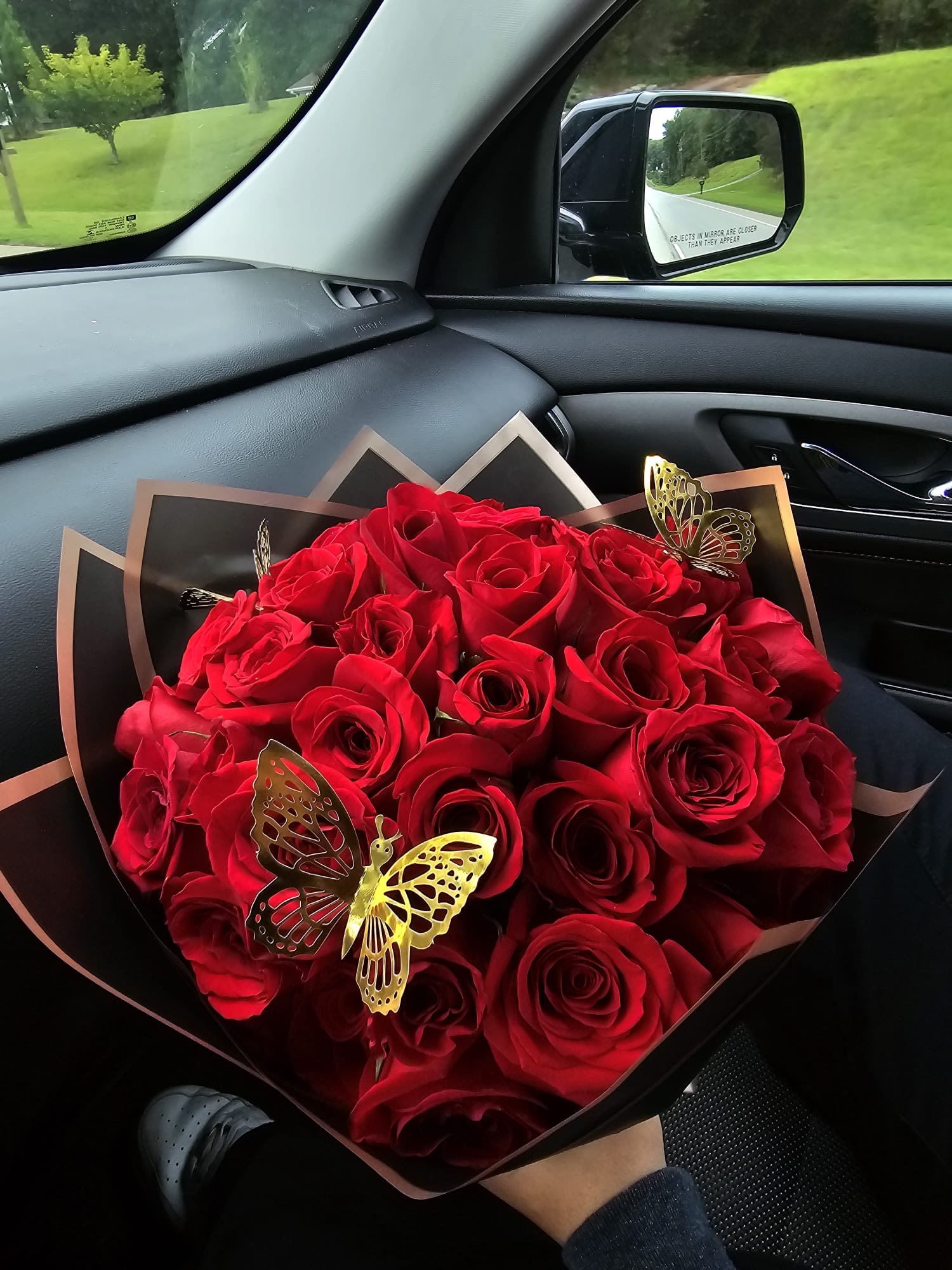 Bouquet of red roses wrapped in black paper with butterfly accents