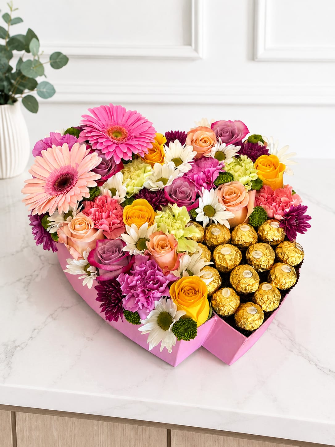 Heart-shaped box of mixed flowers and gold-wrapped chocolates