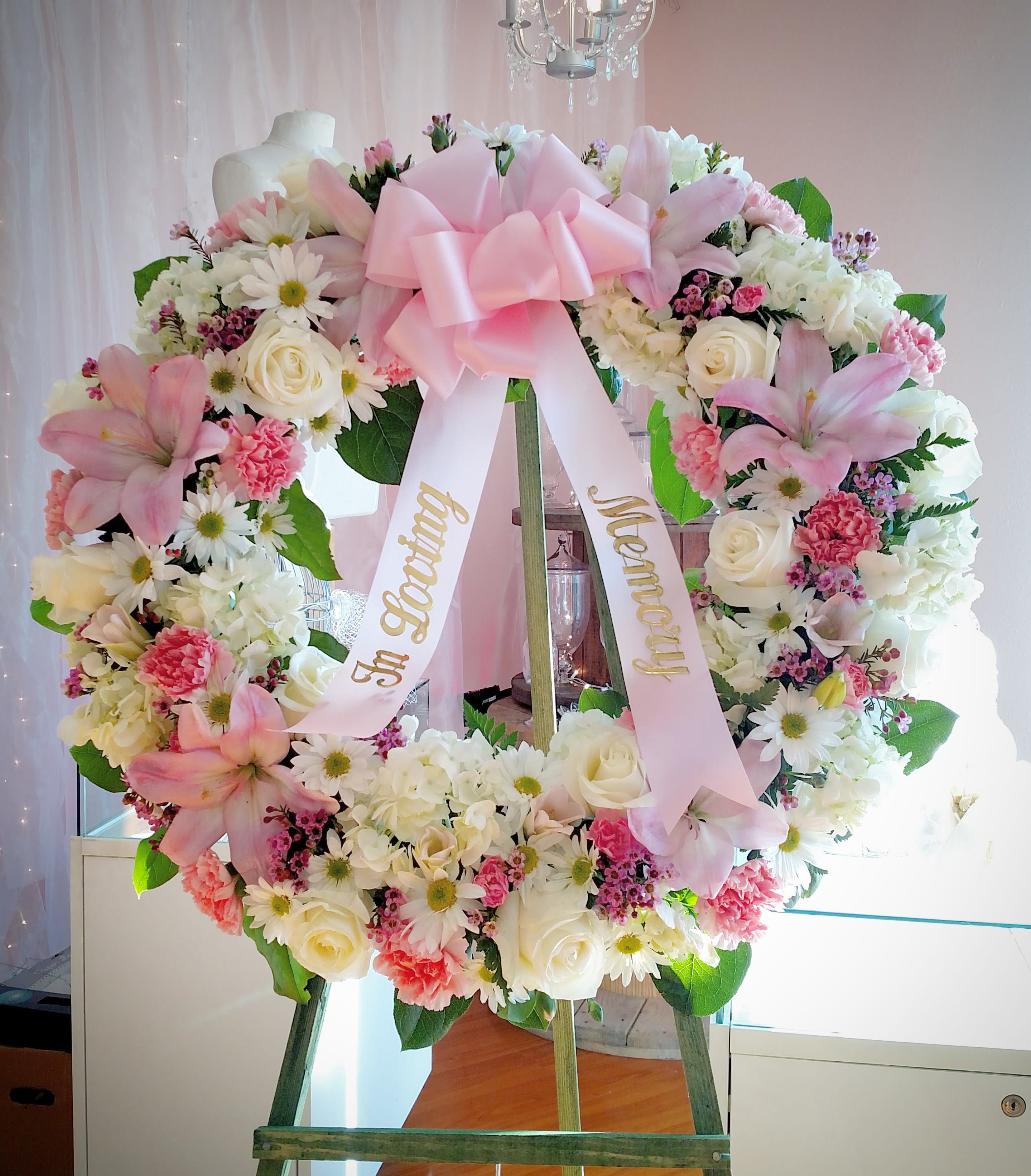 Pink and white floral wreath with a large bow on an easel