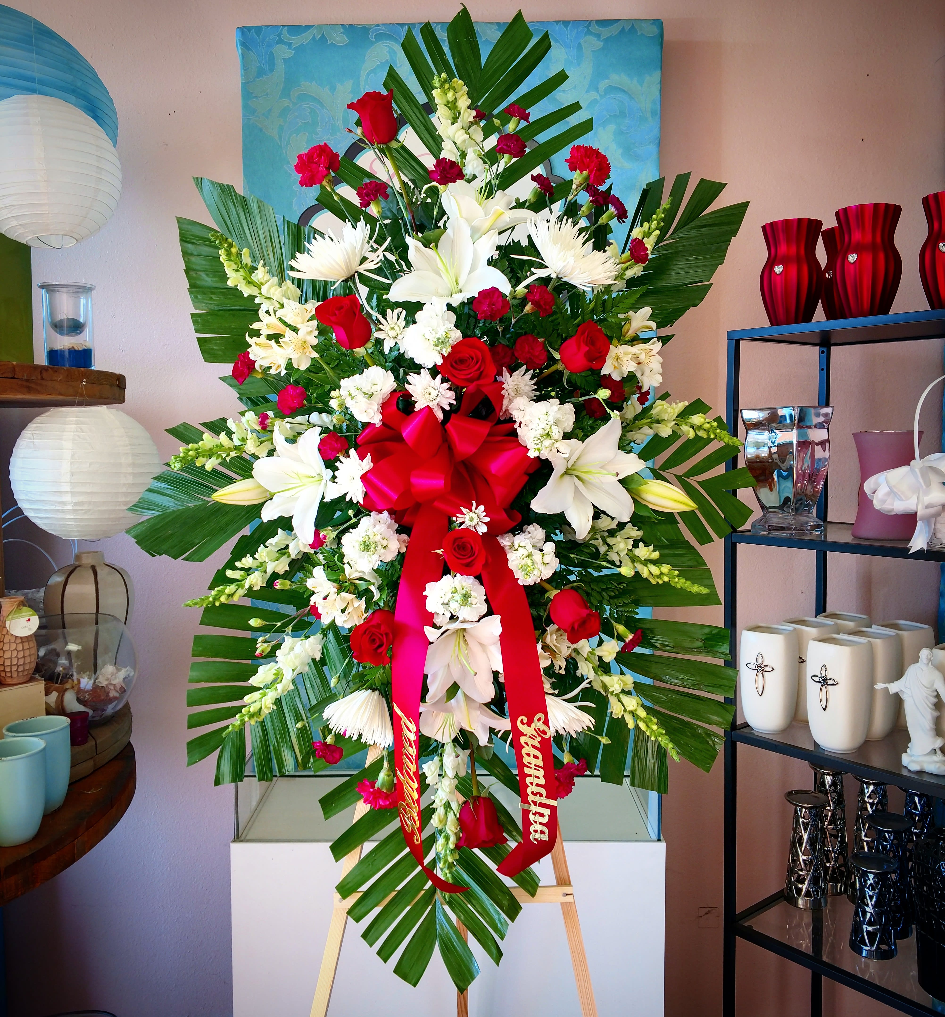 Large standing floral spray with red and white flowers and a red ribbon