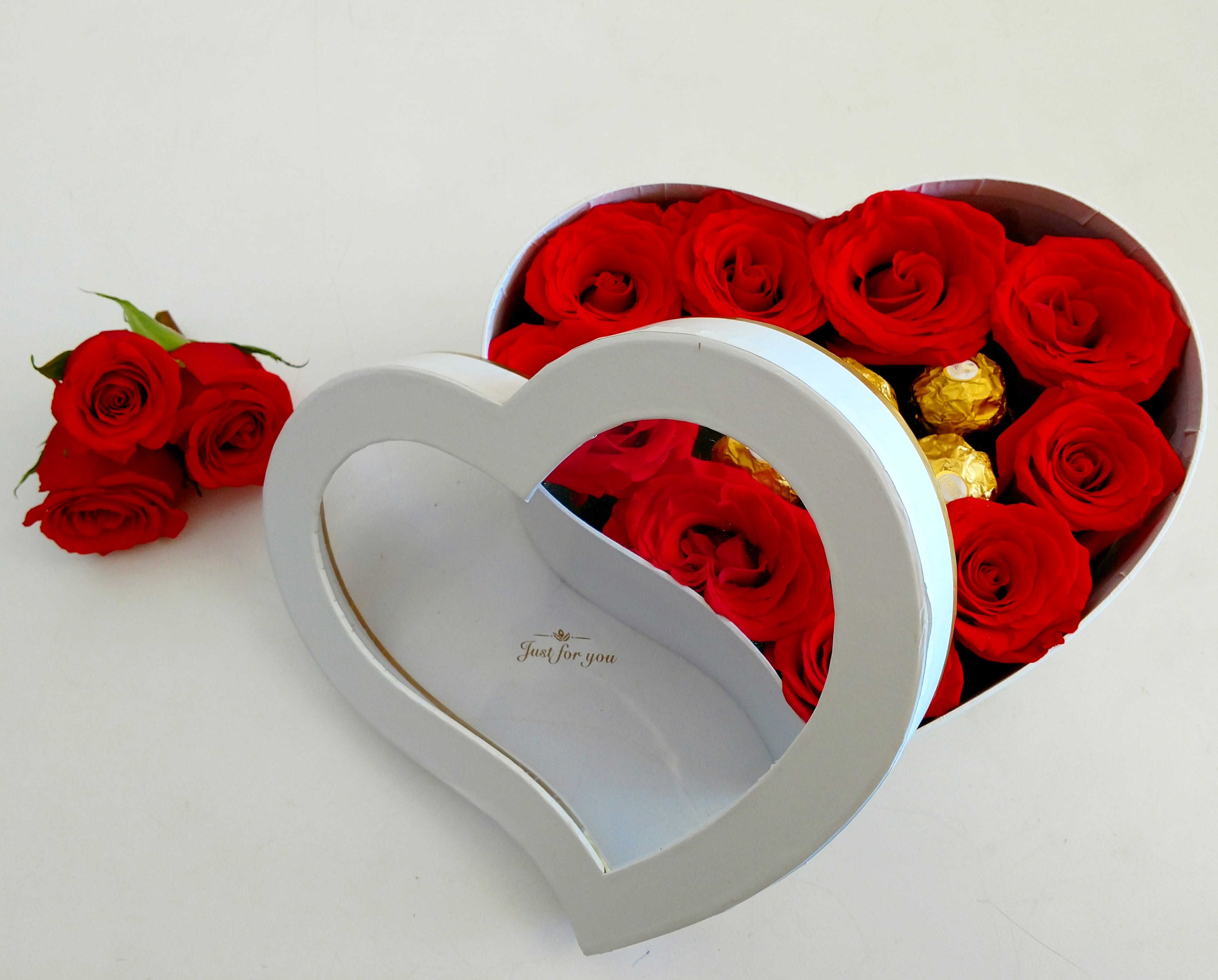 Red roses in a heart-shaped gift box with gold chocolates