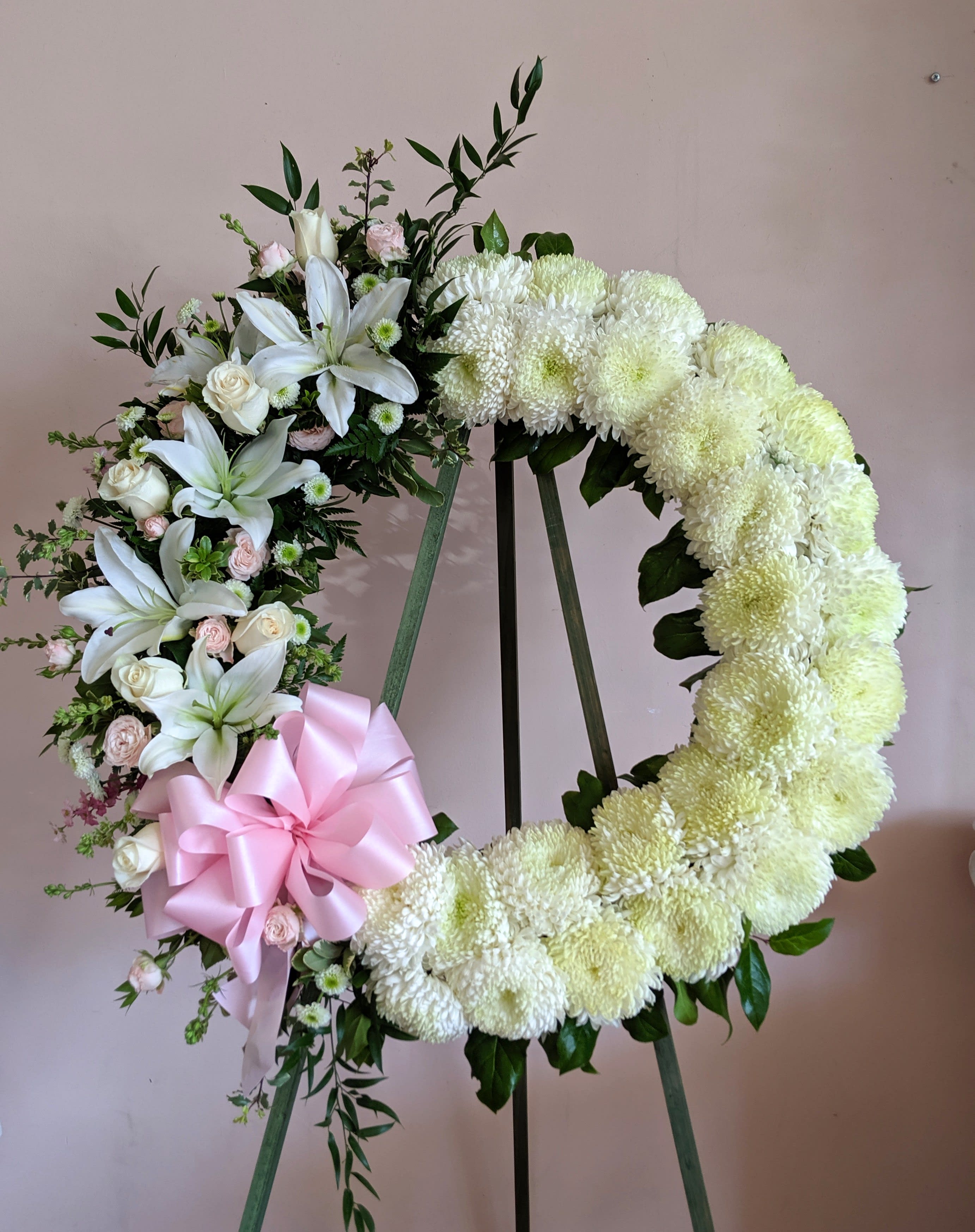 Heart-shaped floral wreath with white flowers and a pink ribbon bow