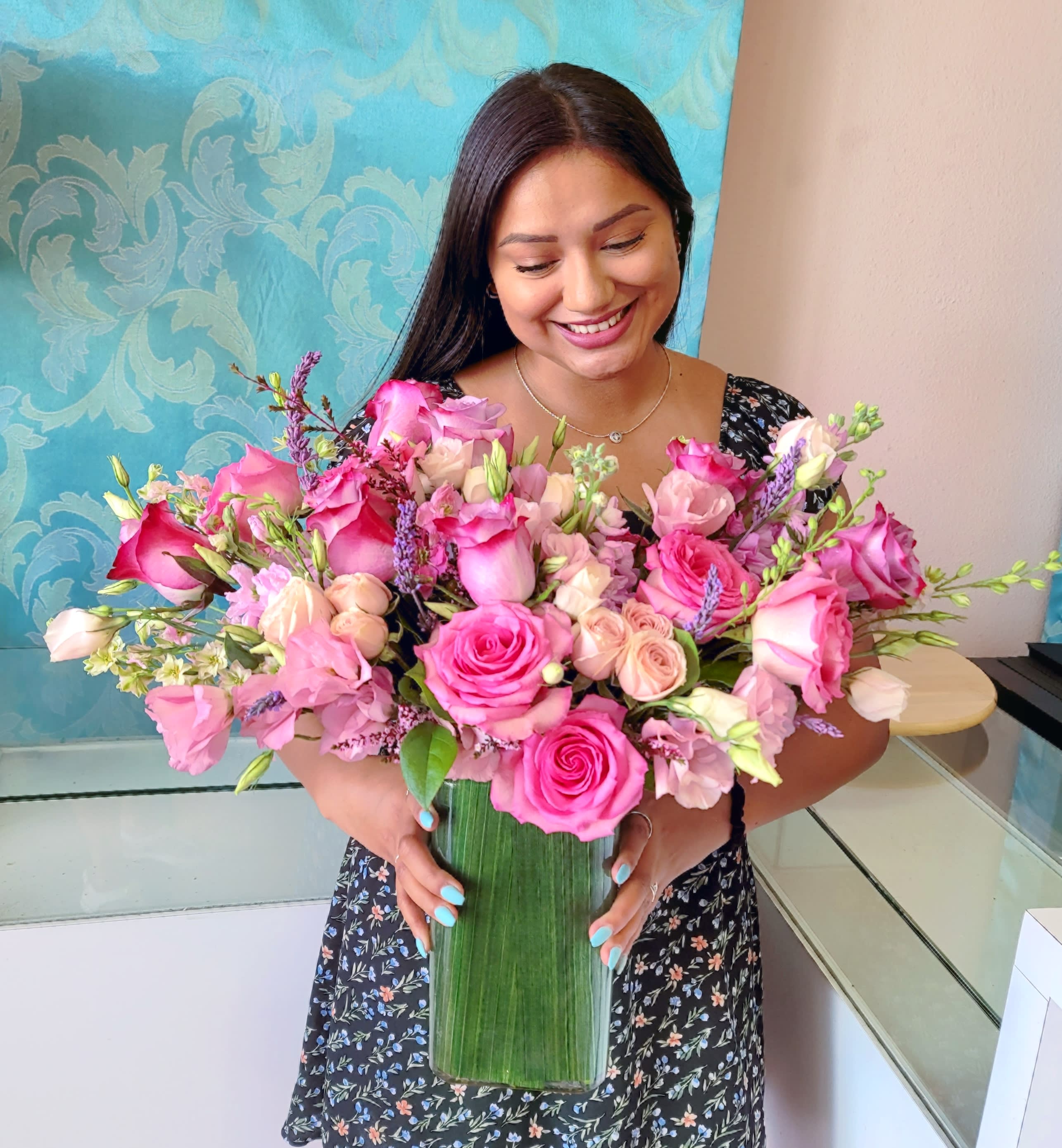 Woman holding a large pink rose bouquet in a tall glass vase