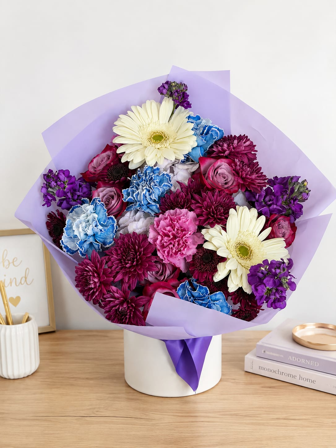 Mixed bouquet of purple, pink, blue, and white flowers in a white box