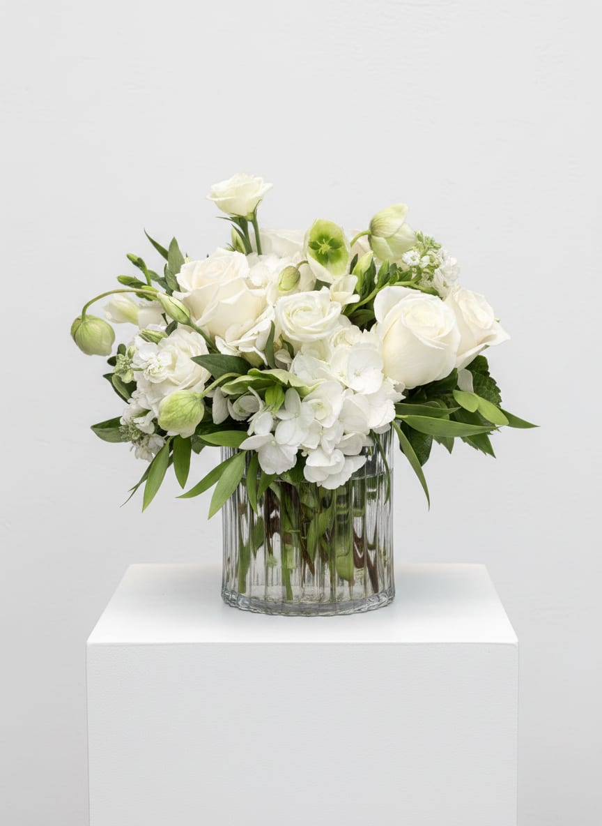 White roses and hydrangeas arranged in a clear glass vase