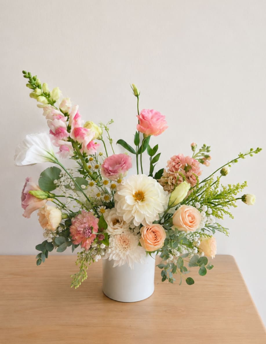 Pastel floral arrangement in a white vase with pink and cream blooms