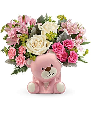 Teleflora's Precious Pink Bear Bouquet - Honor a precious arrival with gorgeous cream roses and delicate pink blooms, beautifully bundled in a sweet ceramic teddy bear keepsake. This precious bouquet includes crÃ¨me roses, pink spray roses, pink alstroemeria, pink miniature carnations, bupleurum, dusty miller, and leatherleaf fern. Delivered in a pink Bundle of Love Bear.