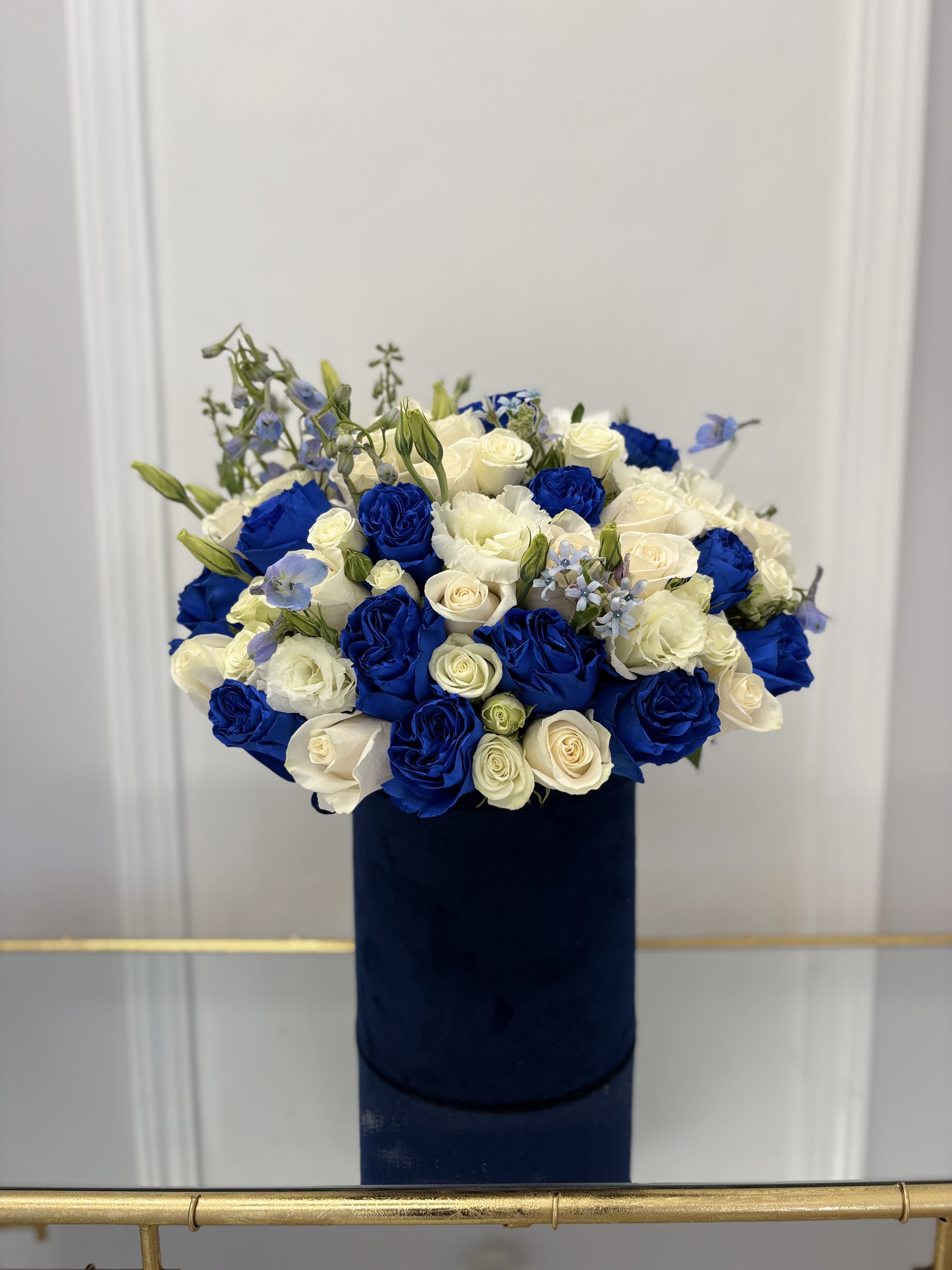 Blue and white rose bouquet in a dark cylindrical box