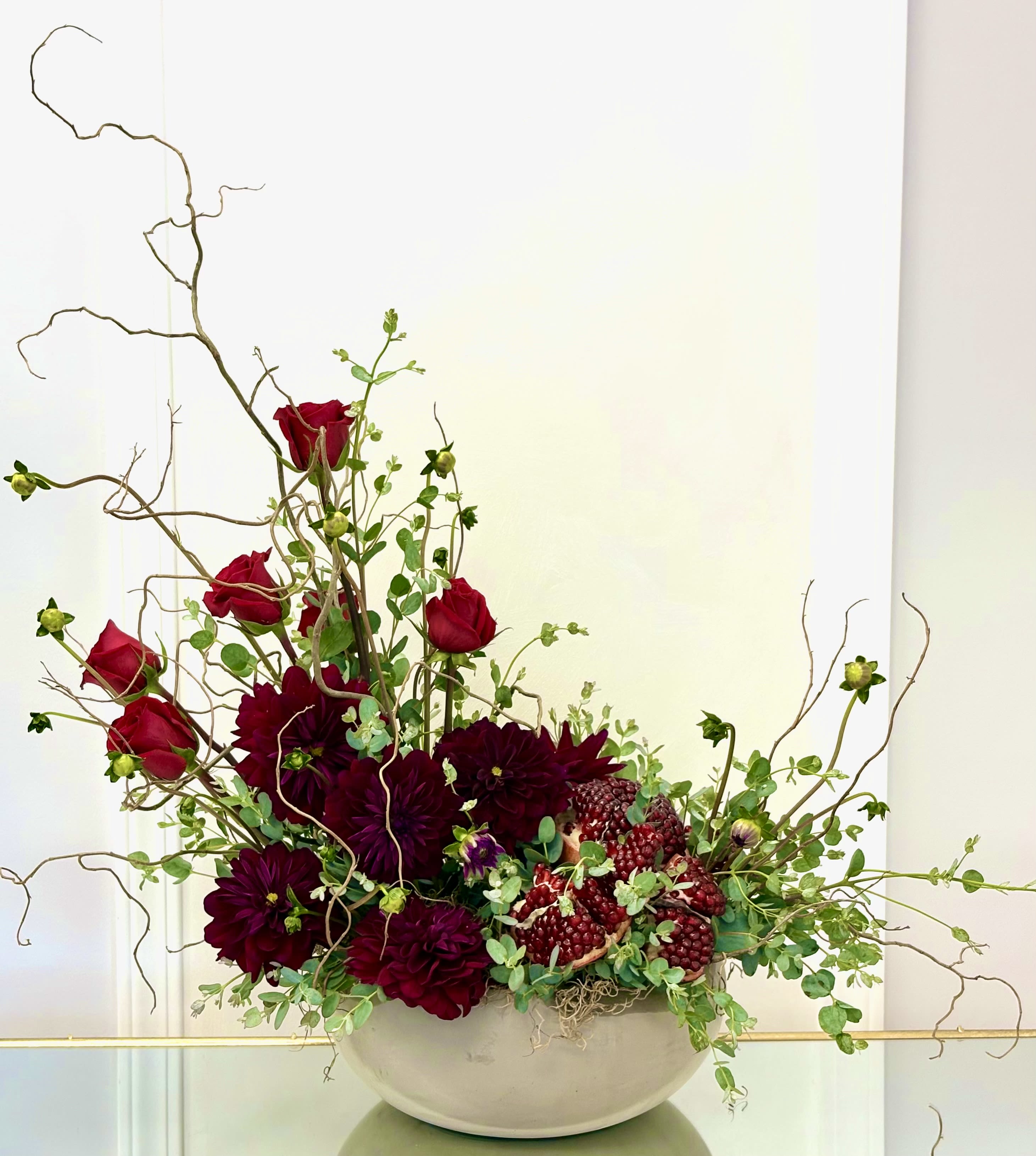 Red roses and dark burgundy dahlias in a white bowl vase