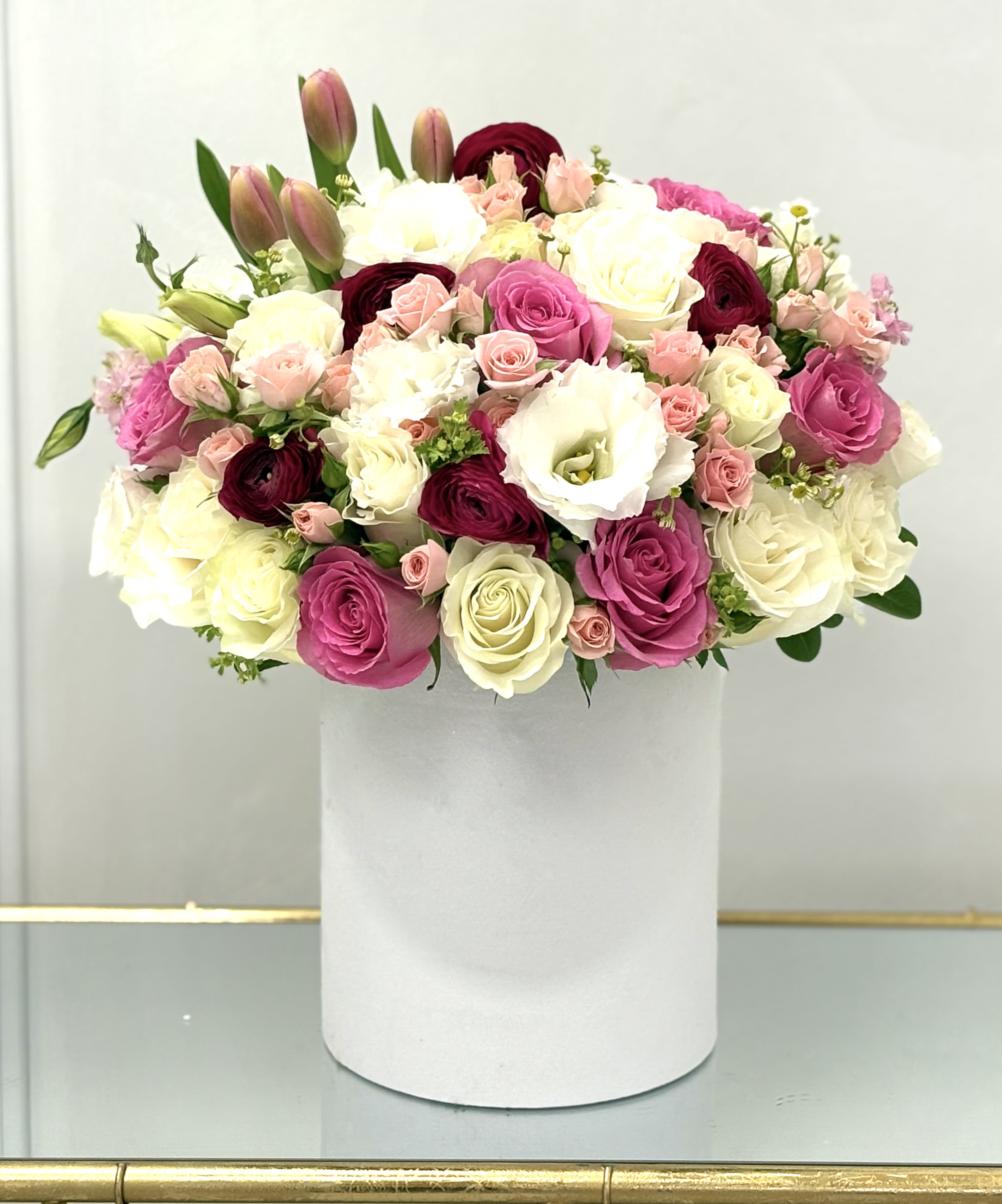 Mixed pink, white, and burgundy flowers arranged in a white box