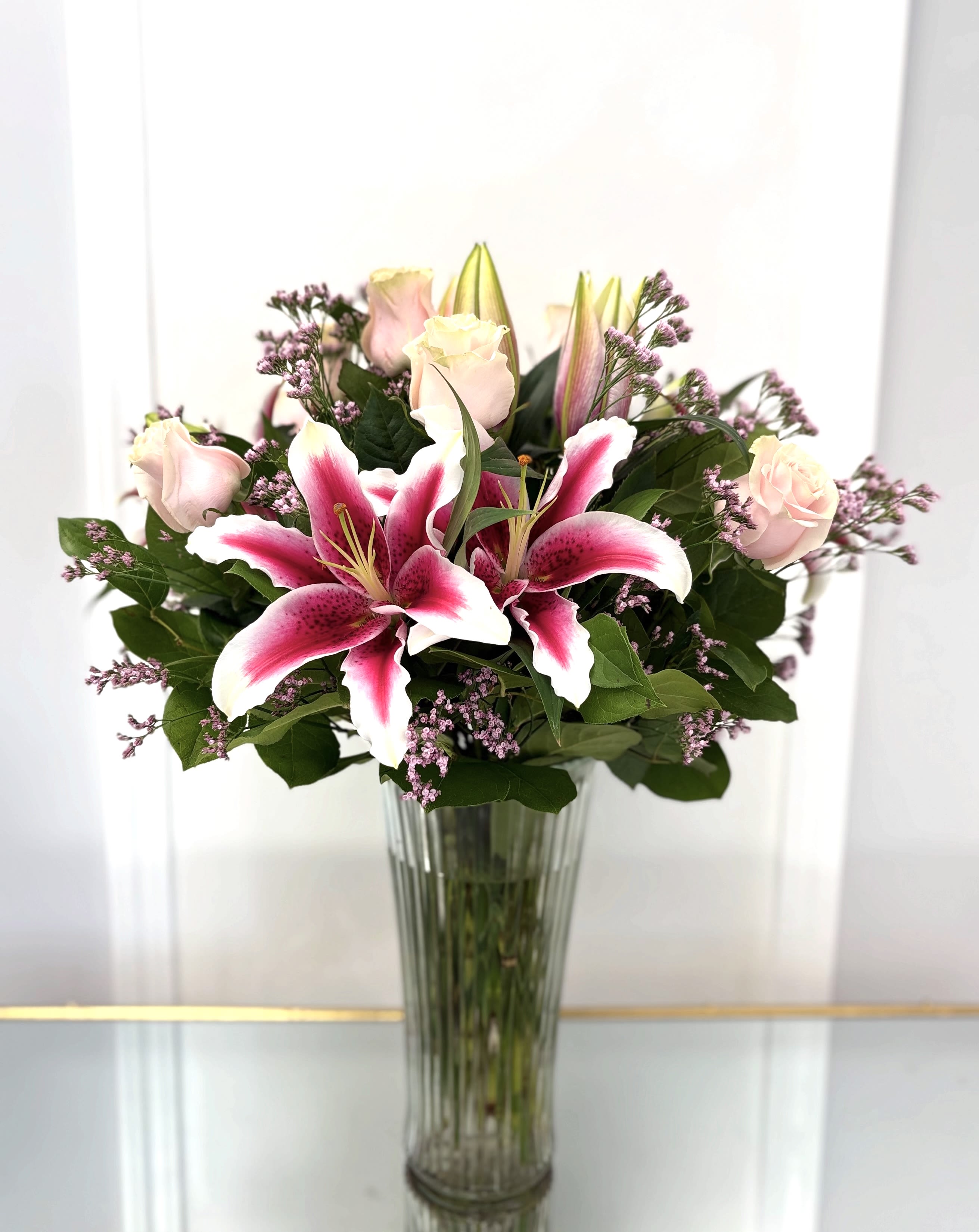 Pink lilies and pale roses in a tall glass vase