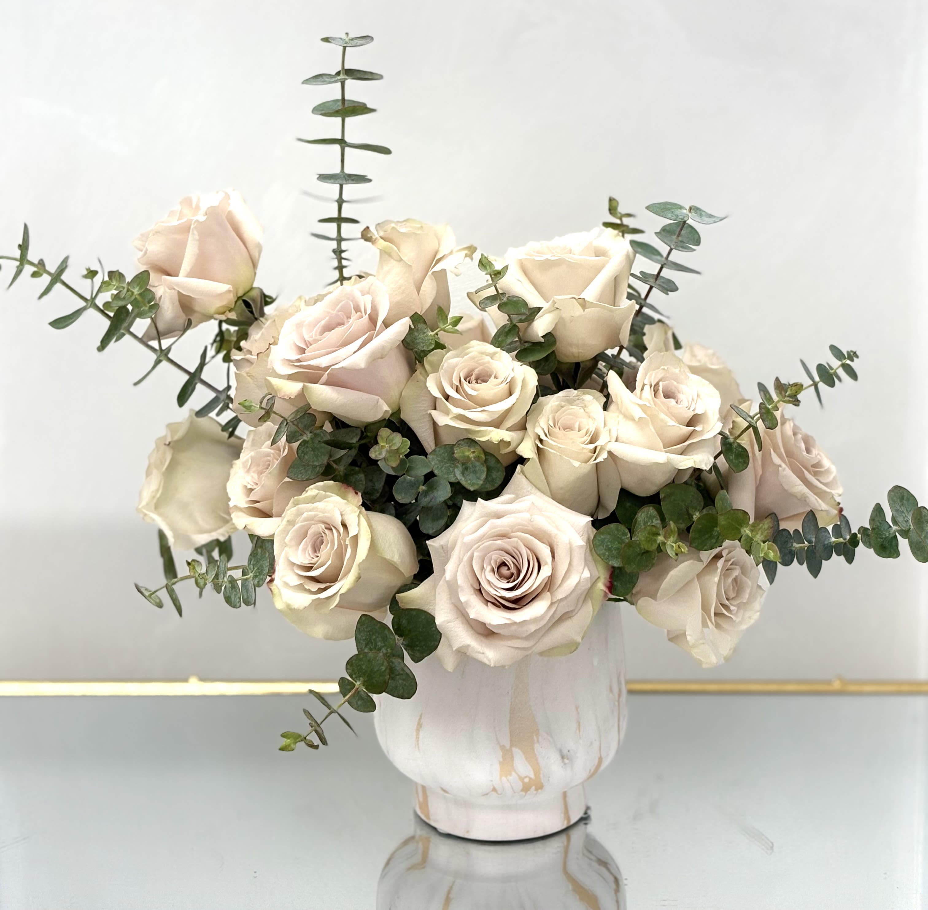Cream rose bouquet in a white vase with eucalyptus