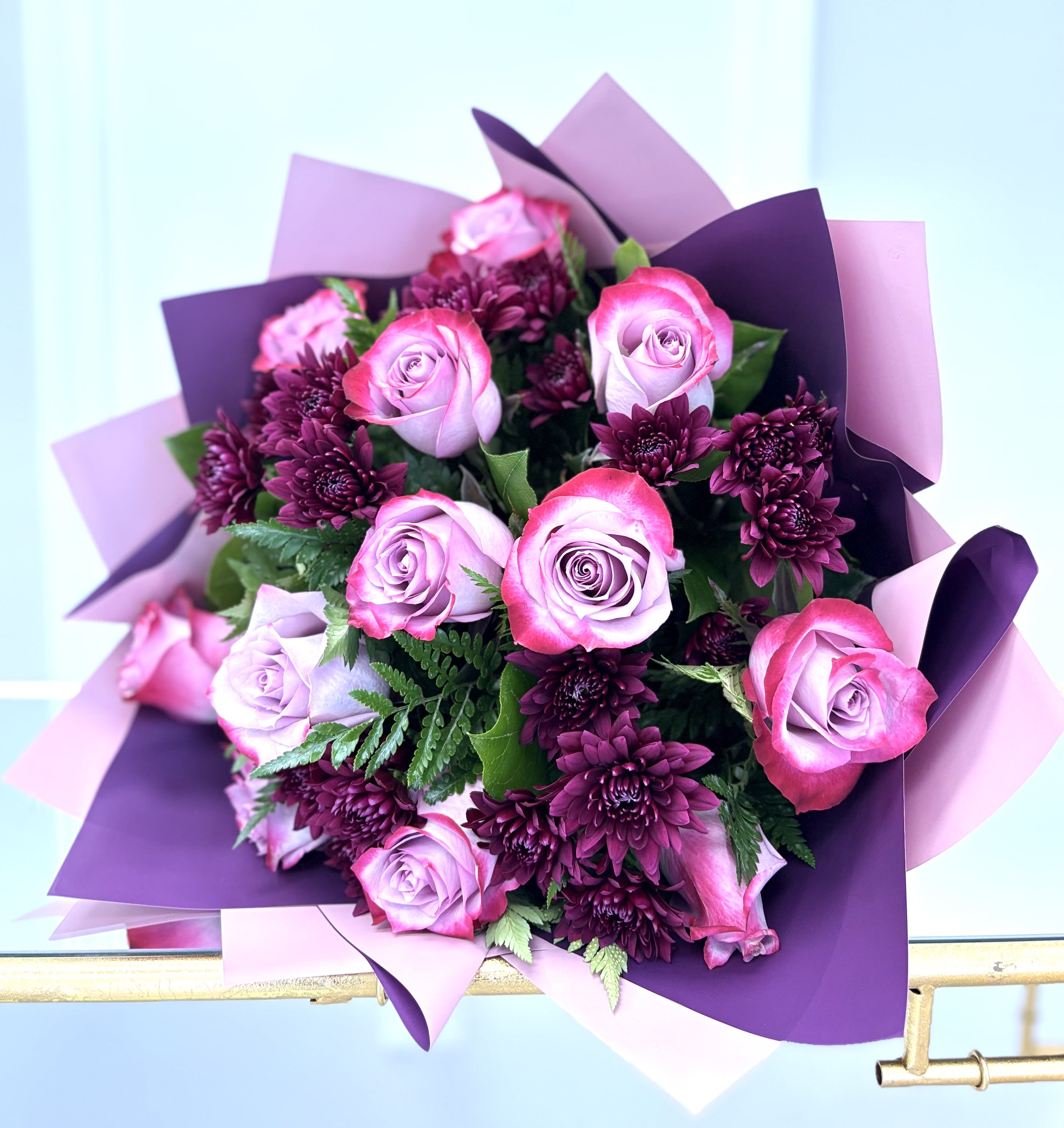 Bouquet of pink roses and dark purple chrysanthemums wrapped in purple paper