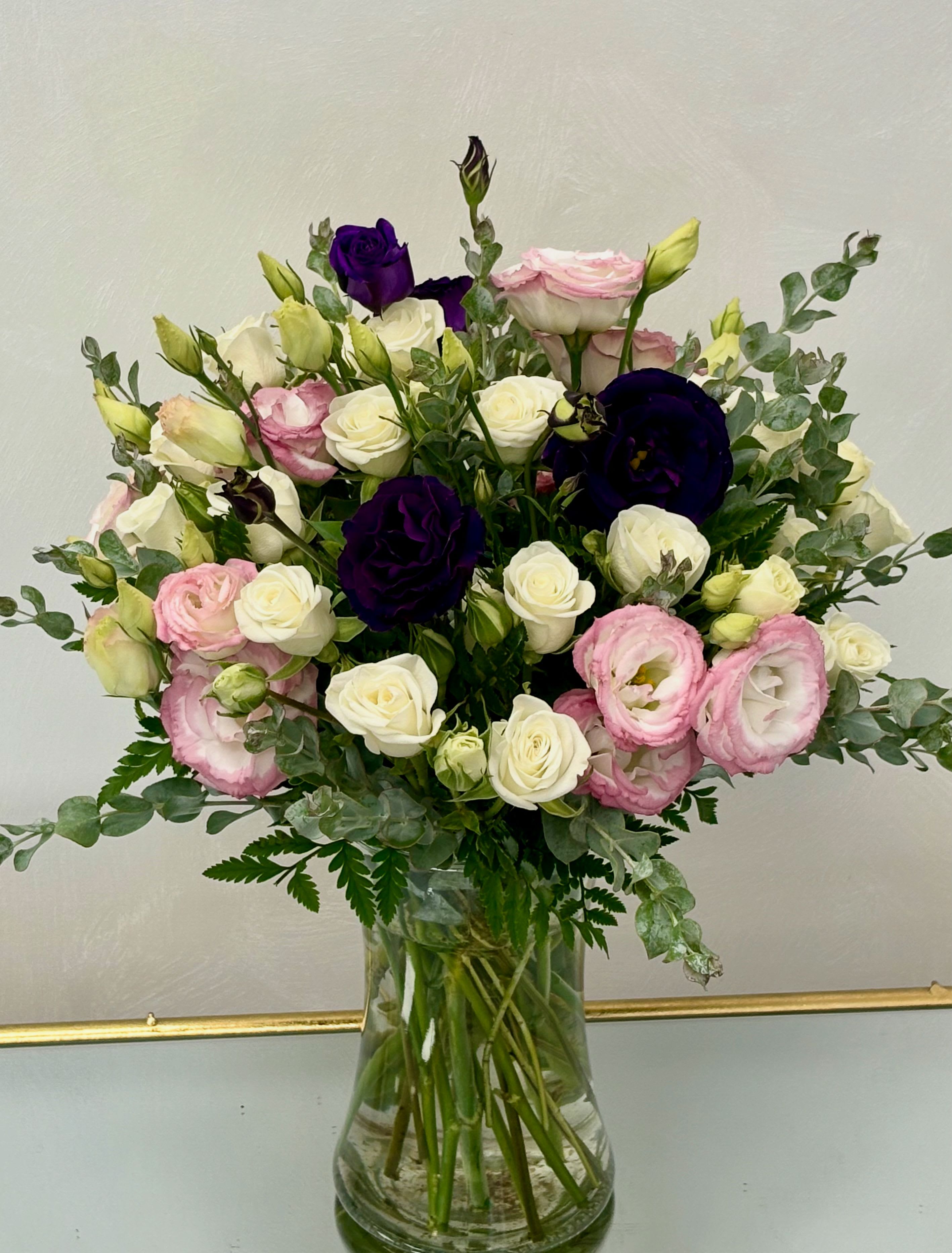 Bouquet of pink, white, and deep purple flowers in a glass vase