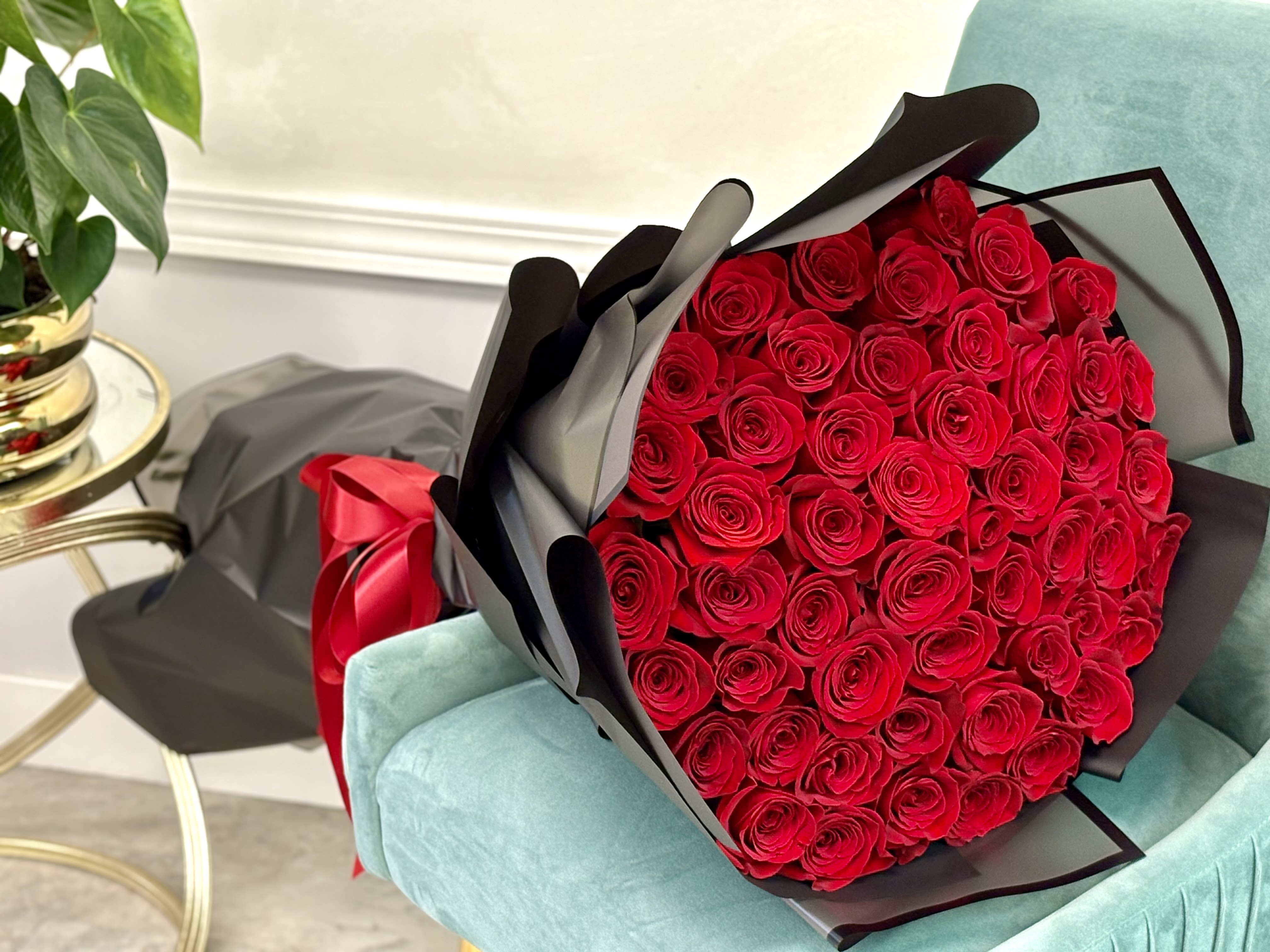 Large bouquet of red roses wrapped in black paper with a red ribbon