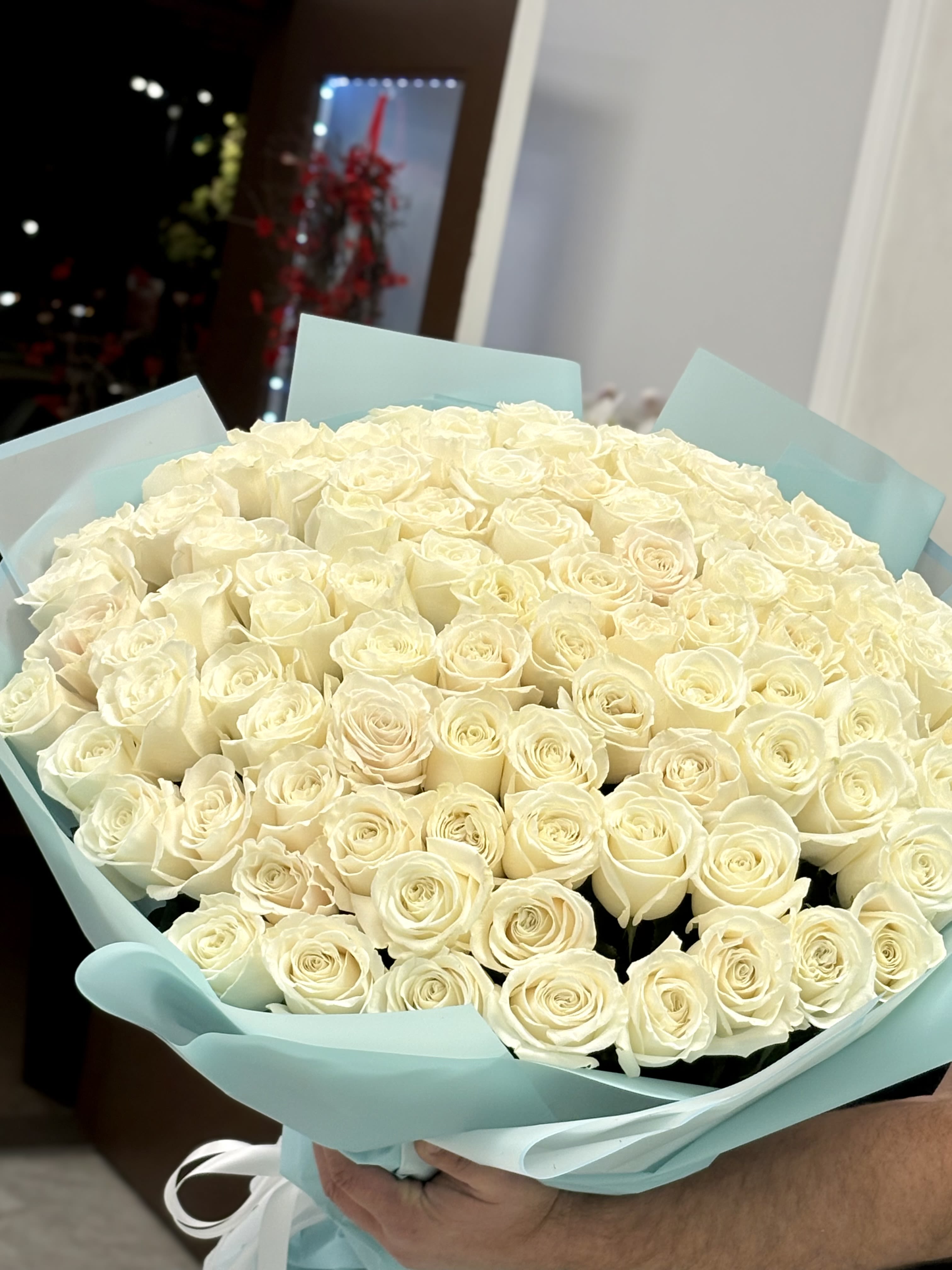 Large bouquet of cream roses wrapped in pale blue paper