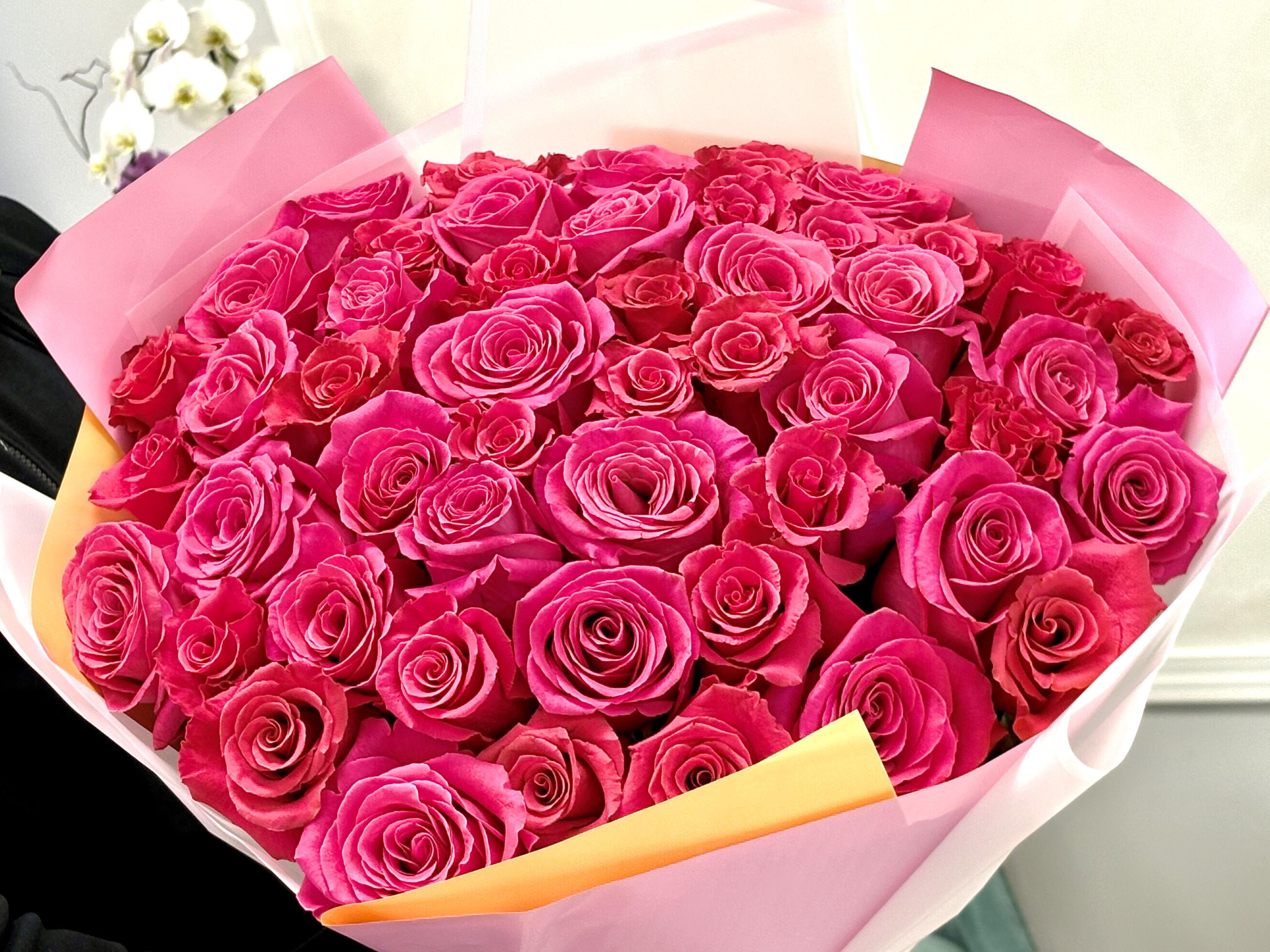 Bouquet of bright pink roses wrapped in pink paper