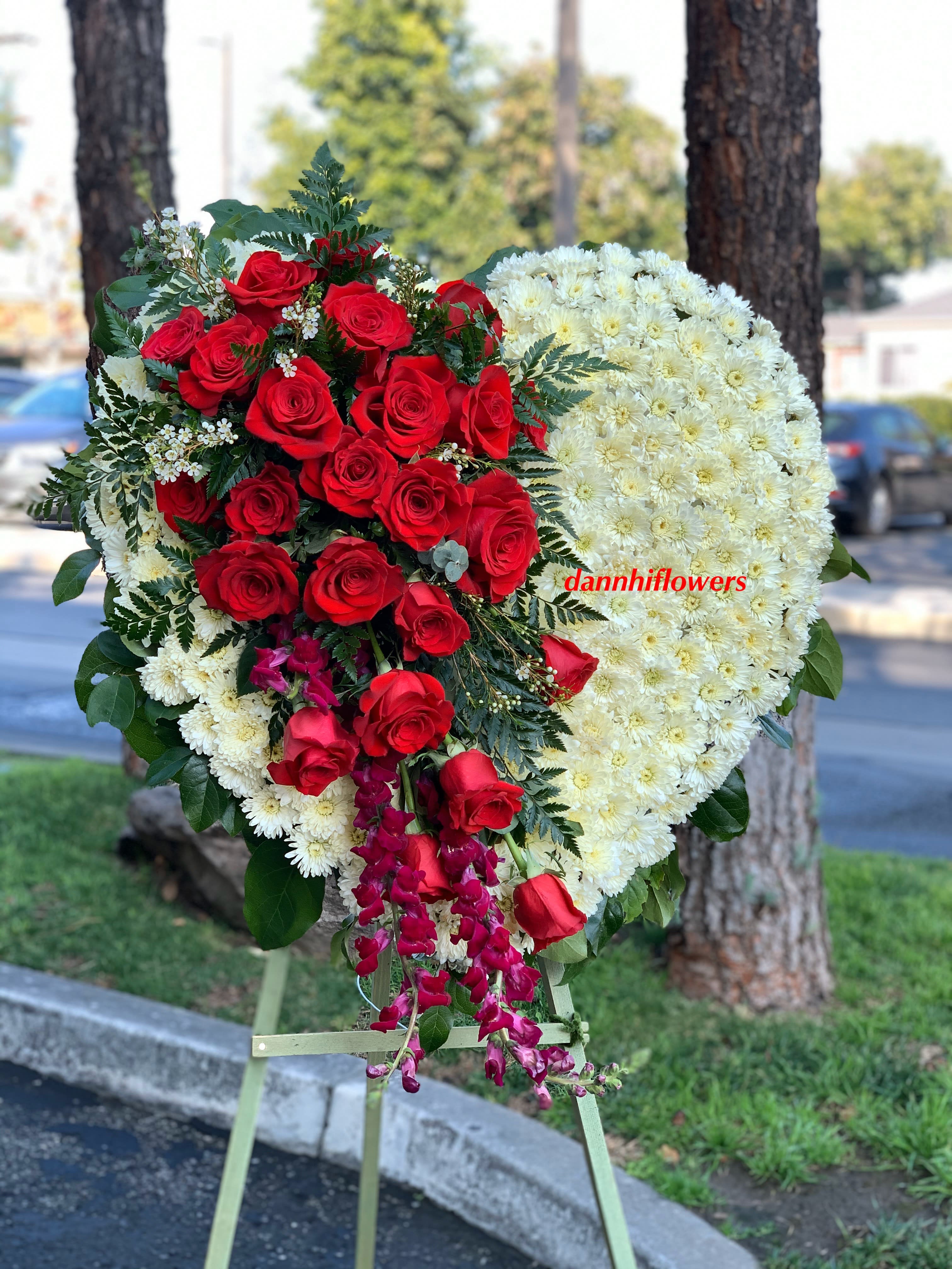 Heart-shaped floral tribute with red roses and white chrysanthemums on an easel