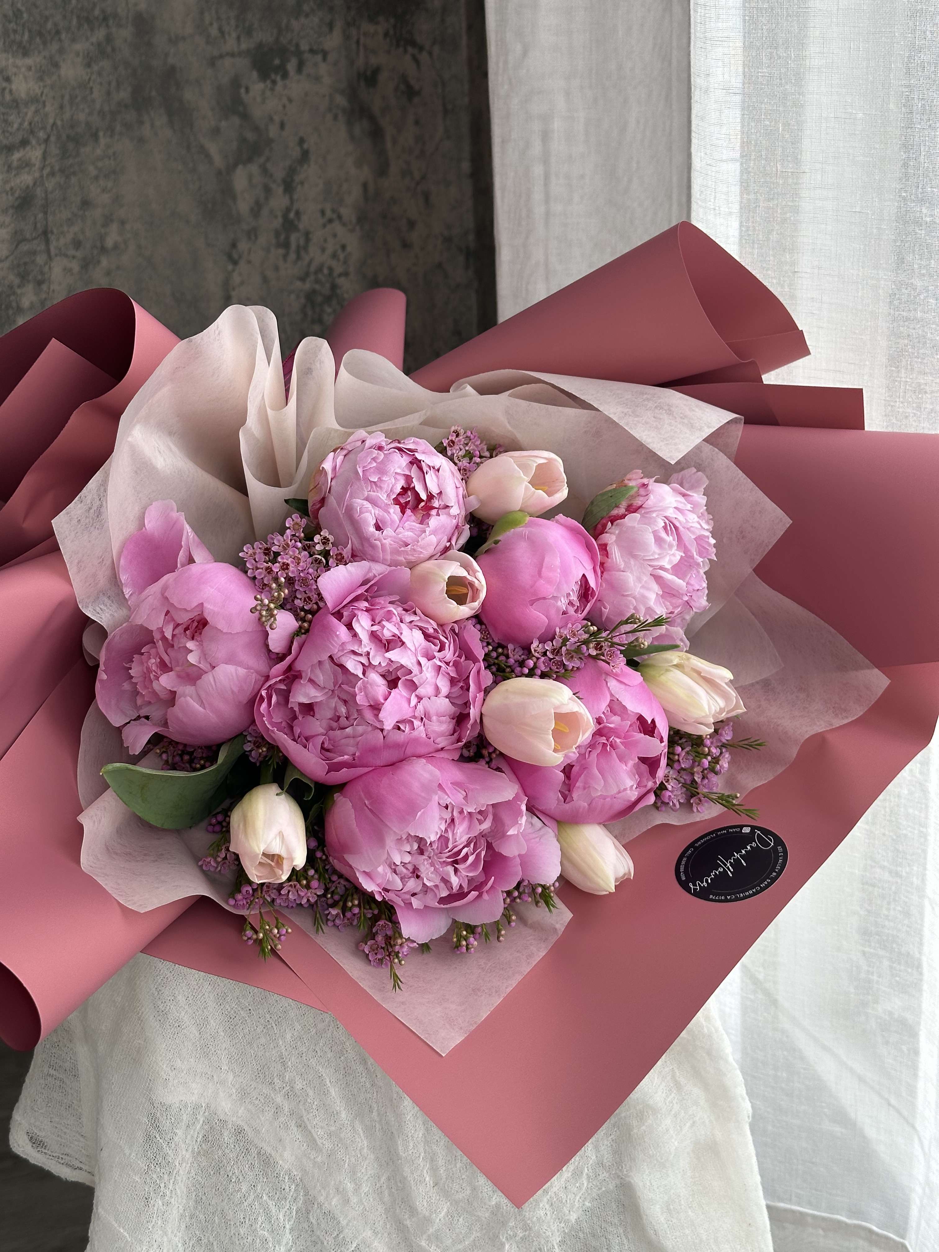 Peonie lovers - This elegant bouquet features a stunning combination of soft pink peonies and delicate pink tulips, creating a beautiful, romantic arrangement. The peonies' lush, full blooms pair perfectly with the graceful tulips, making this bouquet an ideal choice for Valentines, anniversaries, or simply to brighten someone's day. Photo is STANDARD size.   Care Instructions: To keep the flowers fresh, please DO NOT remove them from the flower box, as they are securely arranged in floral foam.  Each day, slowly add water to the gap between the flowers at the center of the box. Make sure the water stays within the cellophane and does not overflow. This will help prevent leaks. The box serves as the container for the arrangement.