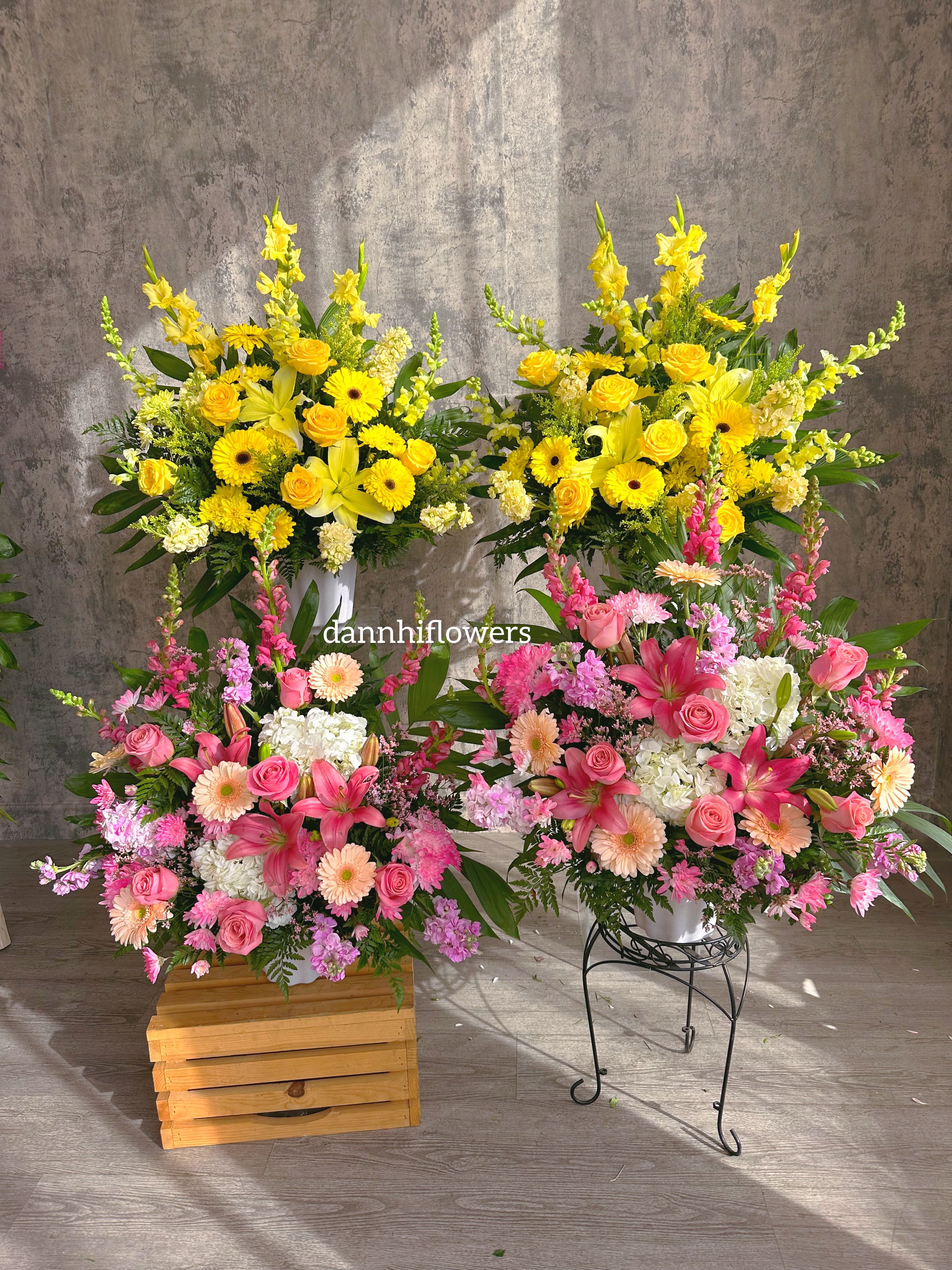 Two large floral arrangements with yellow and pink blooms in white containers