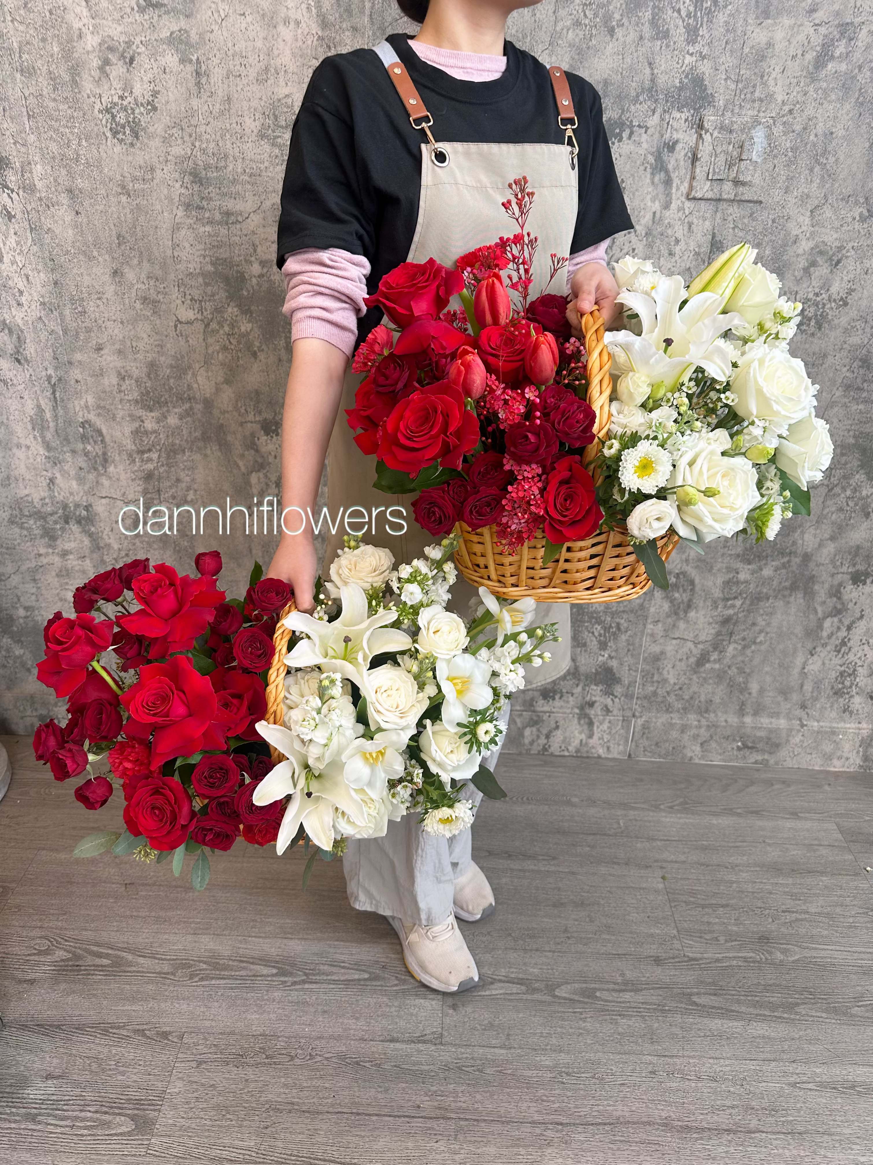 Person holding large baskets of red and white flower arrangements