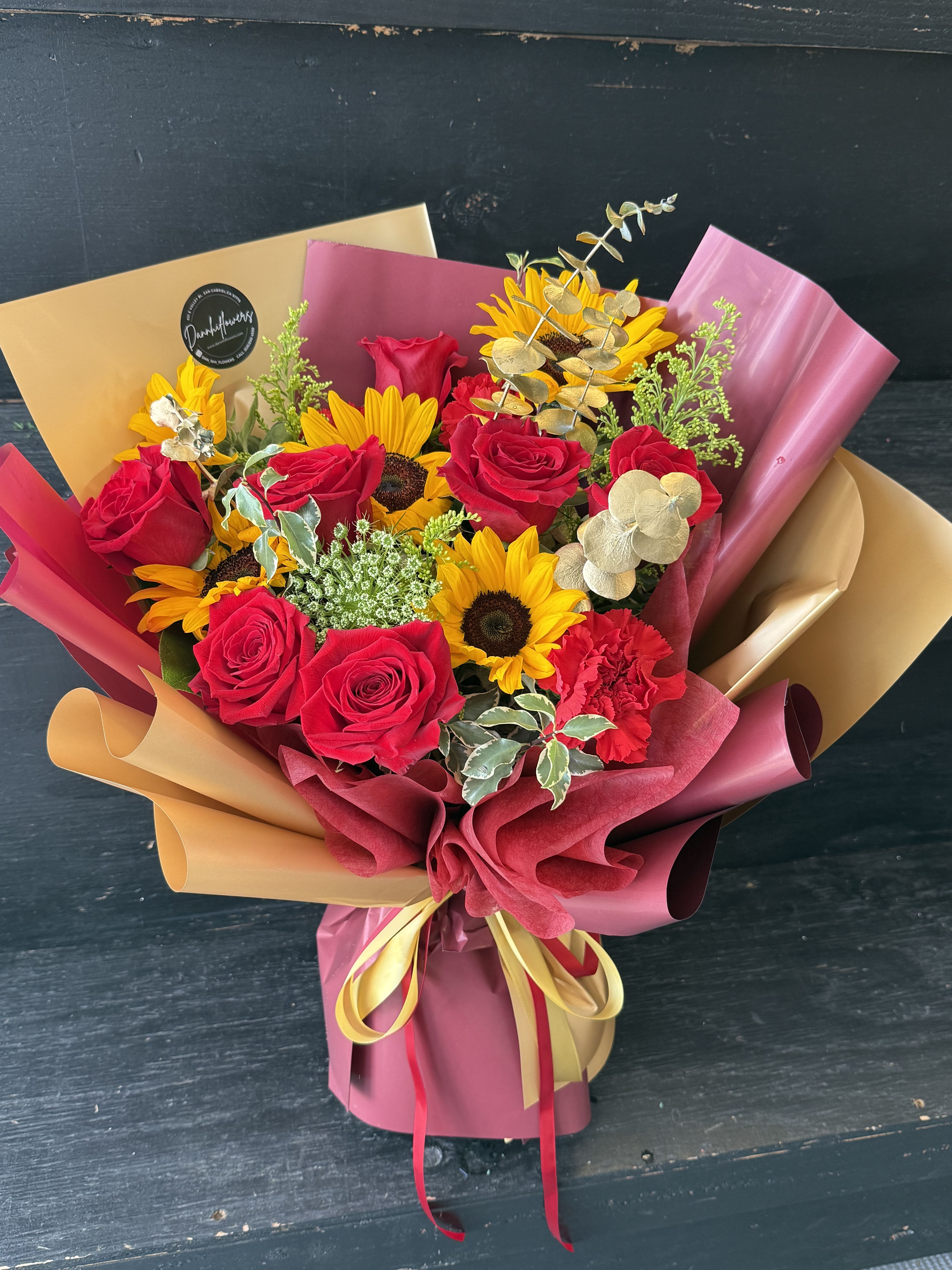 Golden Victory - A bold graduation bouquet inspired by cardinal red and gold — featuring radiant sunflowers, premium red roses, and luxe gold wrapping to celebrate every achievement in style 