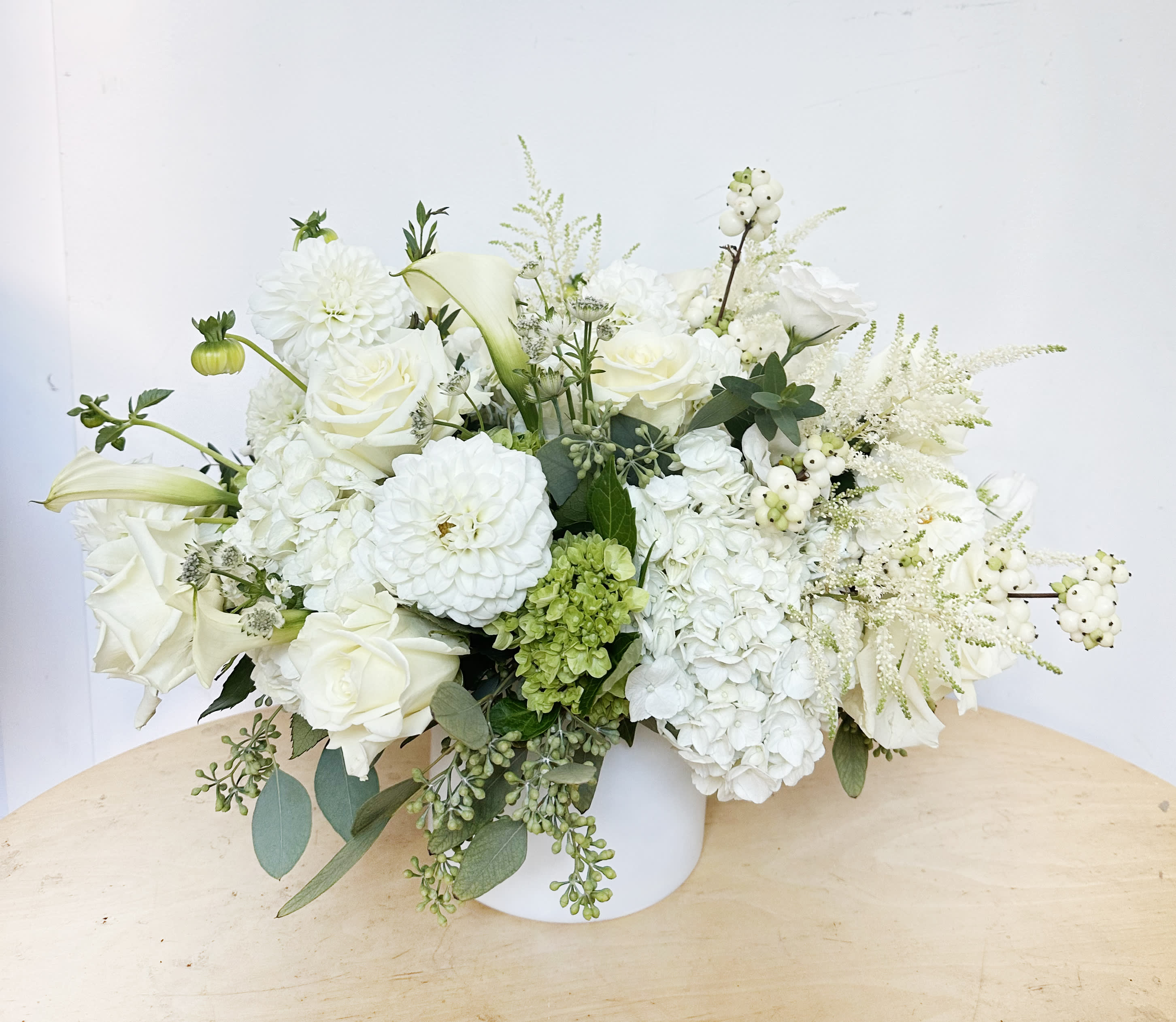 White Paradise  - This arrangement features white hydrangeas, white dahlias, white roses. It presented in a white glass vase. 