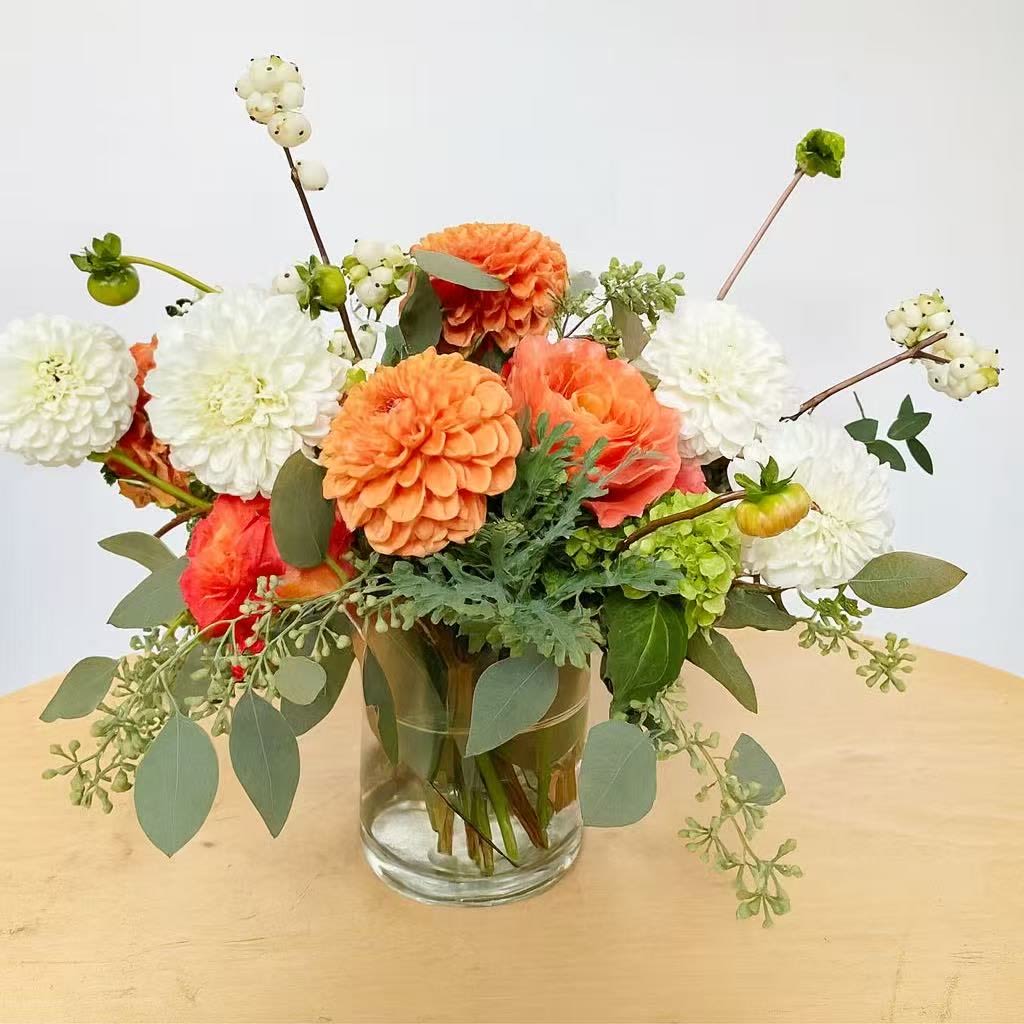 Dahlia Fields - This arrangement is presented in a very unique yellow ceramic vase.  It features white and orange dahlias. The vase may be varied due to availability. 