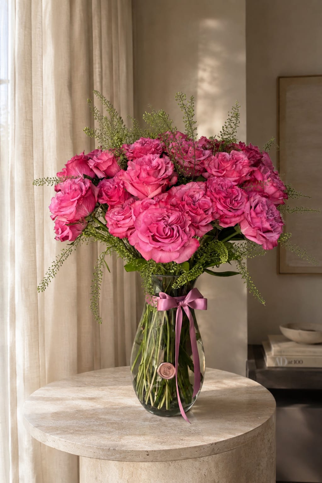 Pink roses arranged in a clear glass vase with a ribbon