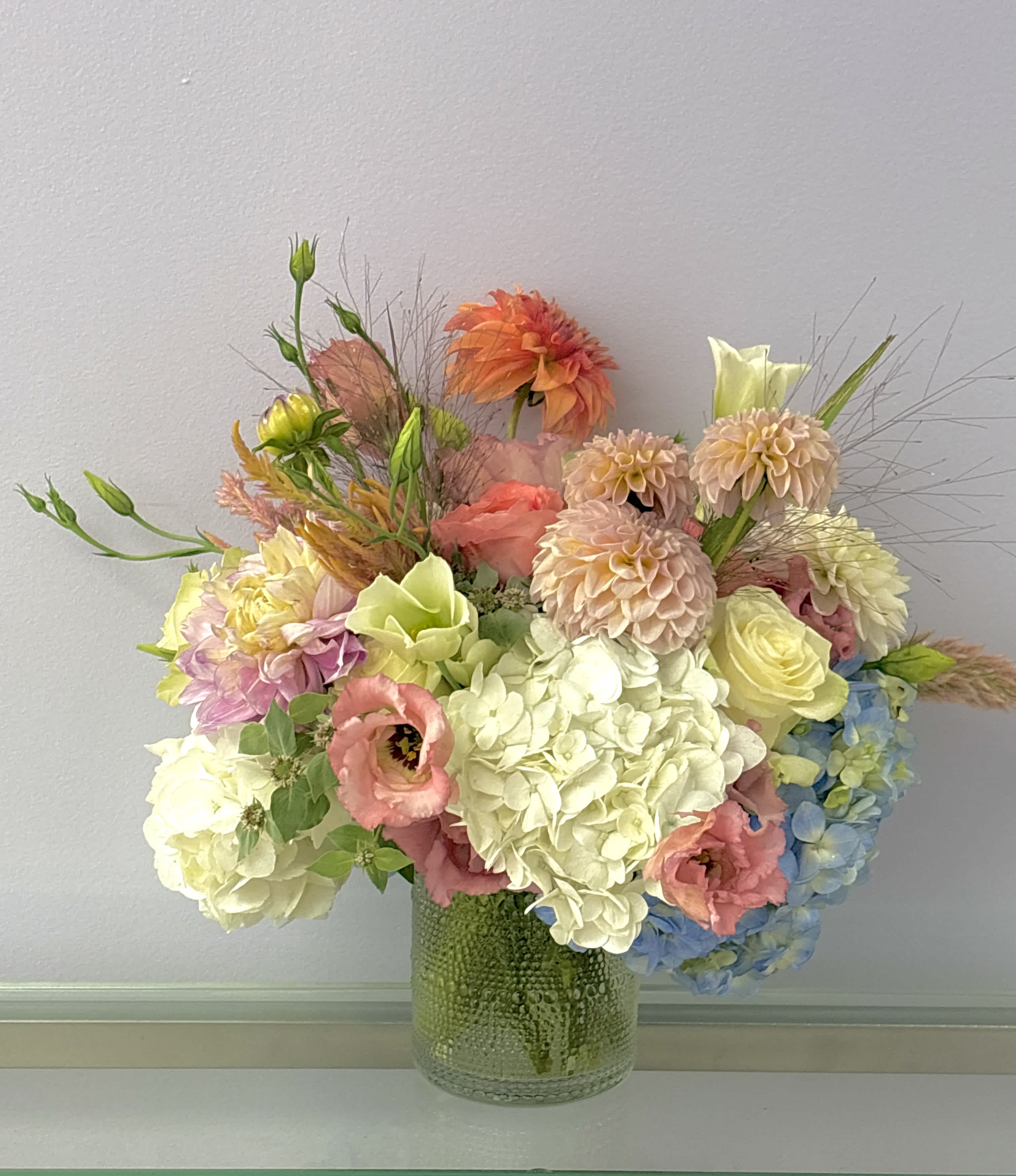 Pastel mixed flower arrangement in a textured glass vase