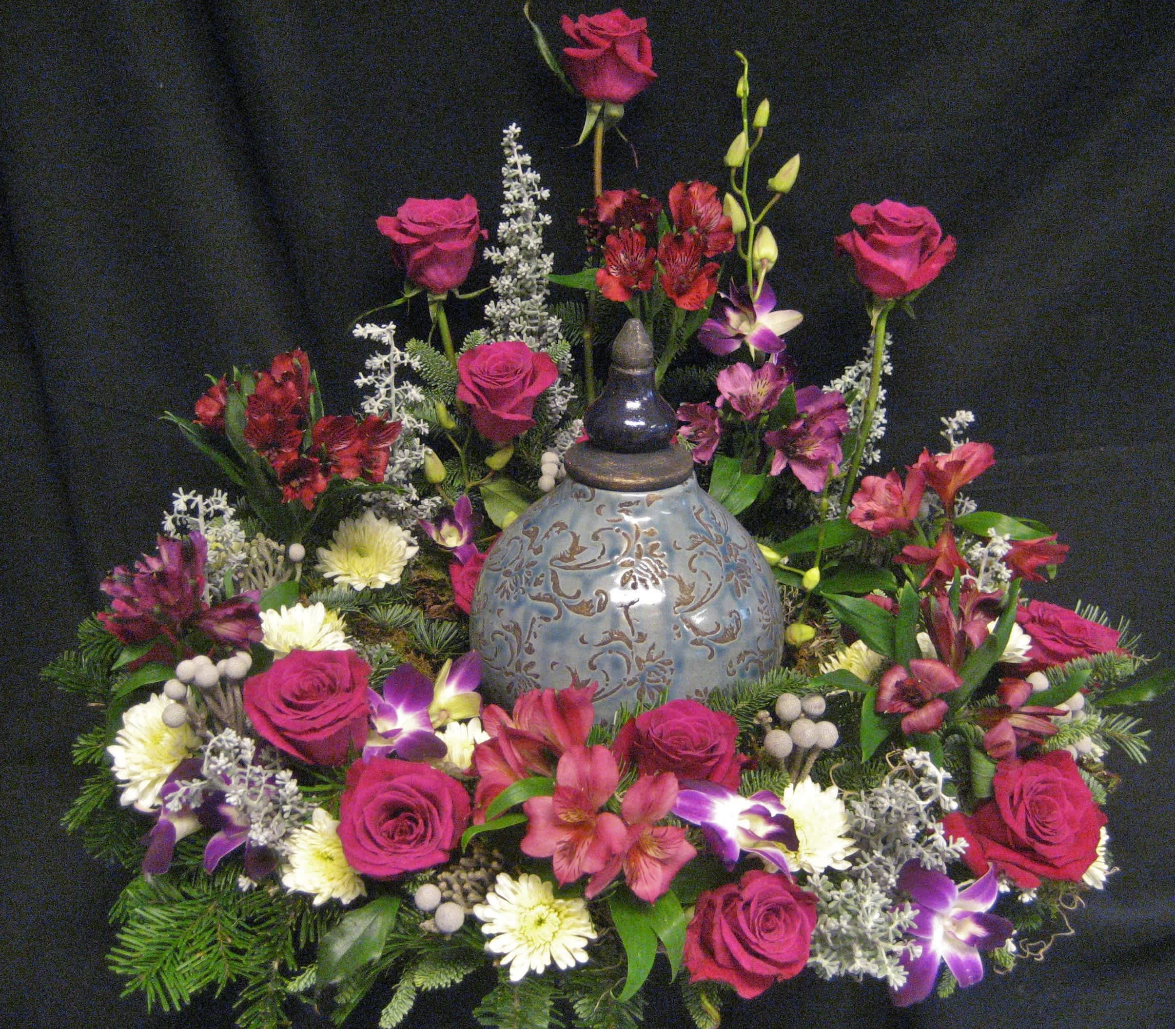Floral arrangement with pink roses and mixed blooms around a decorative urn