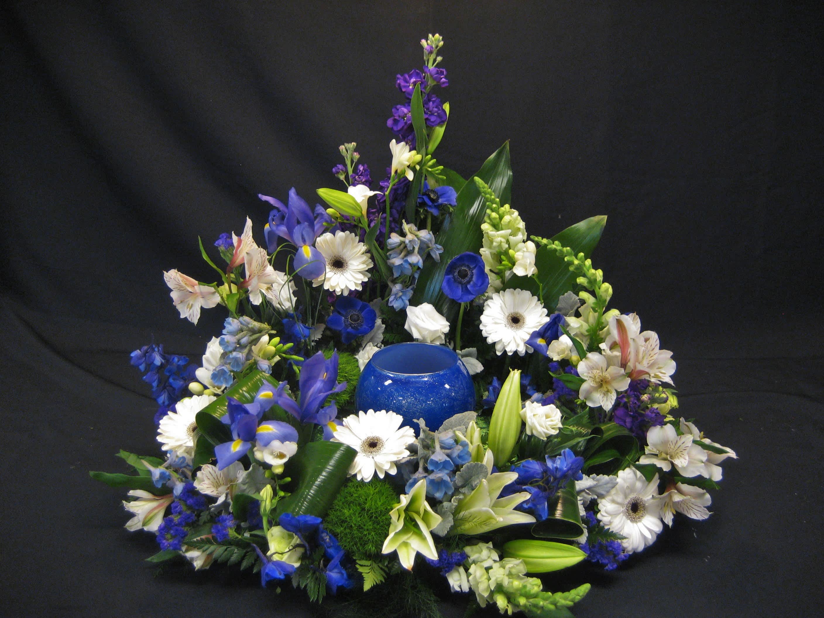 Blue and white floral arrangement with a blue glass candle holder in the center