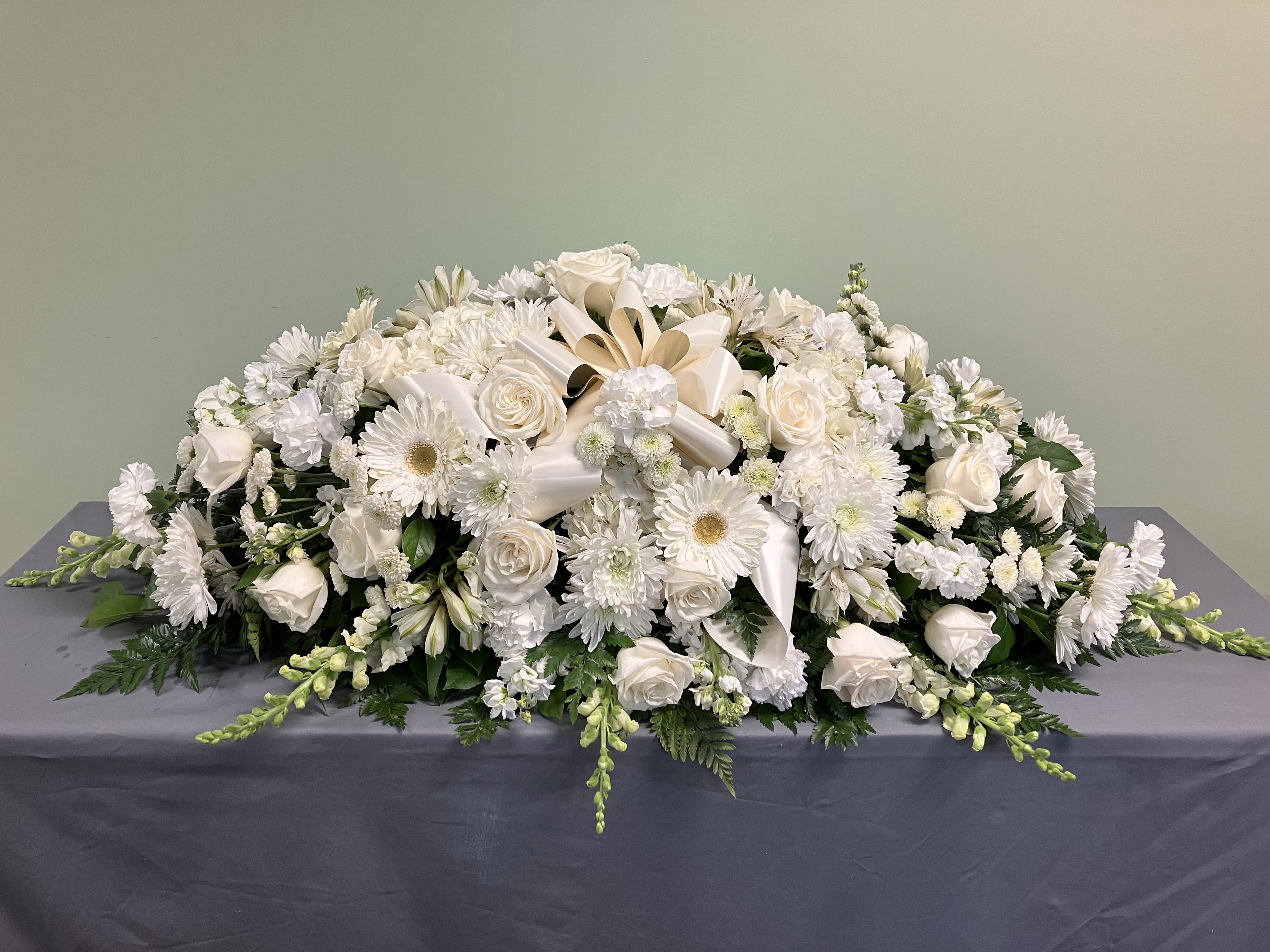 White floral casket spray with roses and daisies
