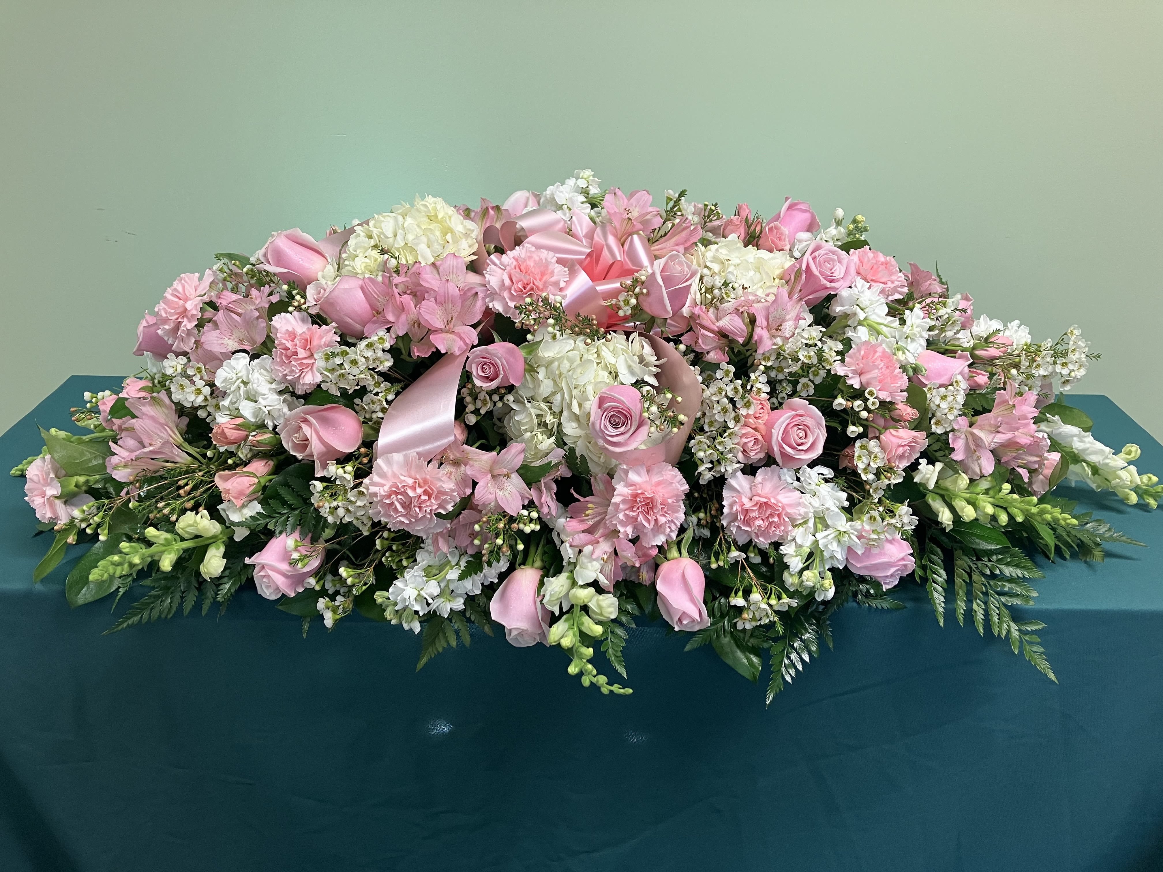 Large pink and white floral arrangement with ribbon accents