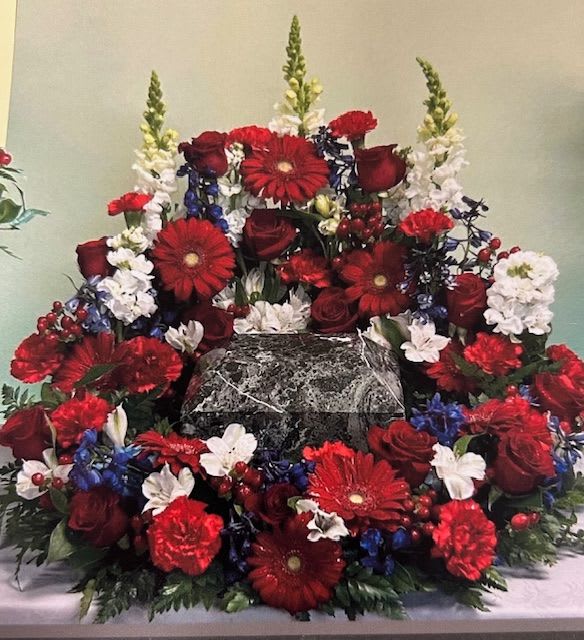 Large red, white, and blue floral arrangement around a marble urn