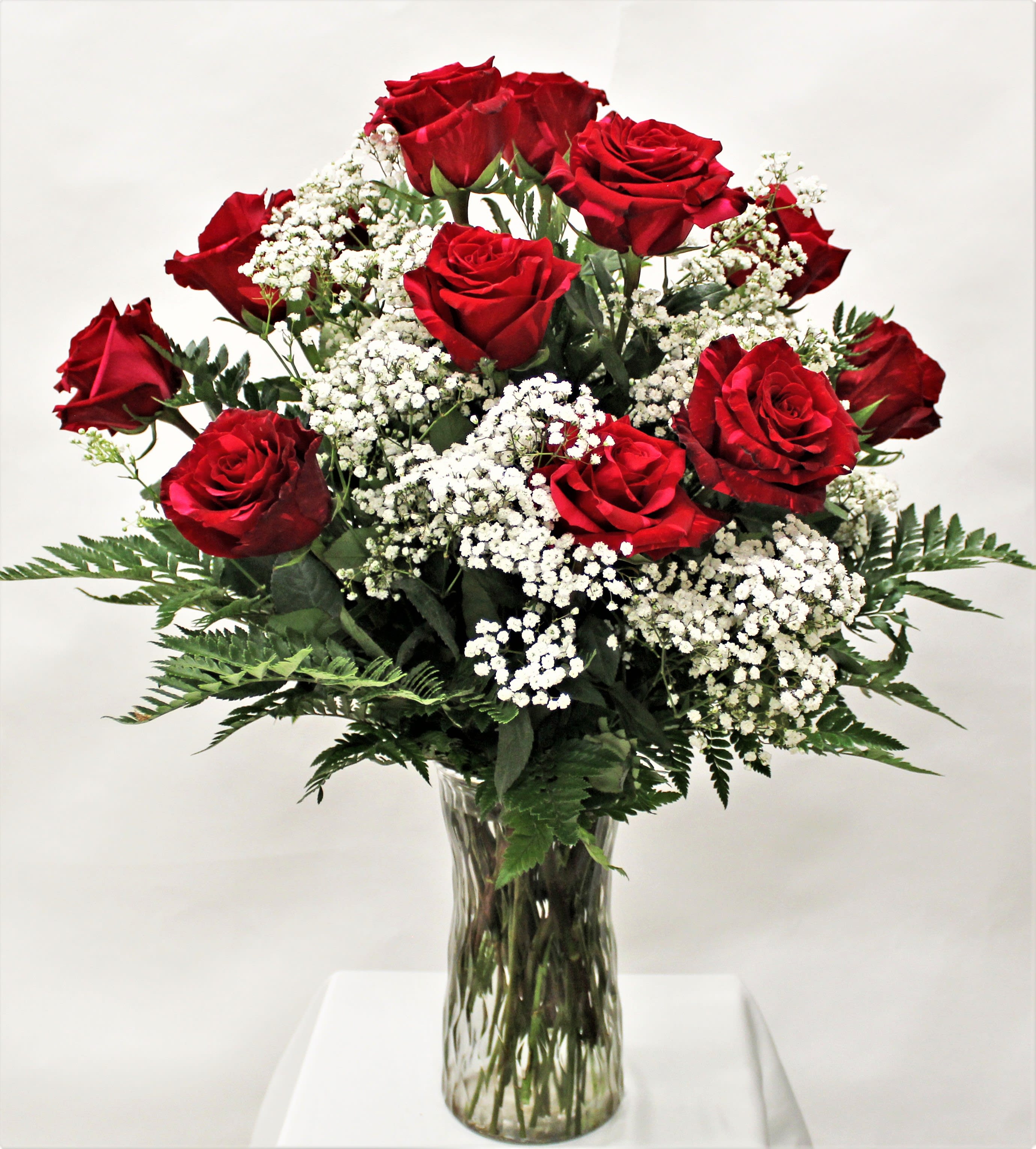 Arrangement of red roses with white filler flowers in a clear glass vase