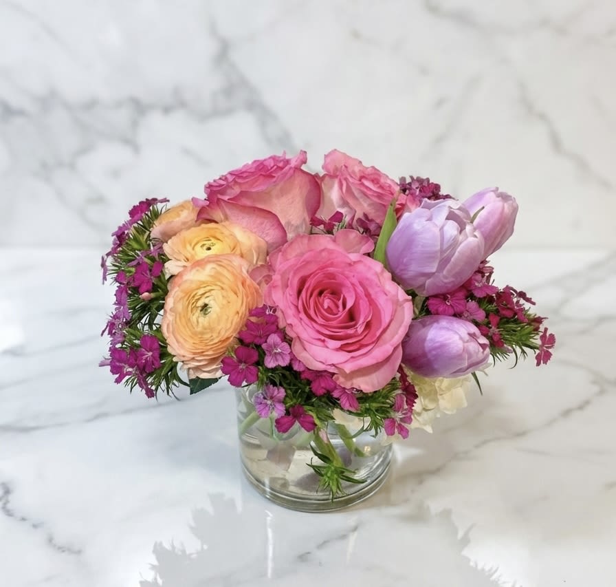 Pink and peach flowers arranged in a clear glass vase